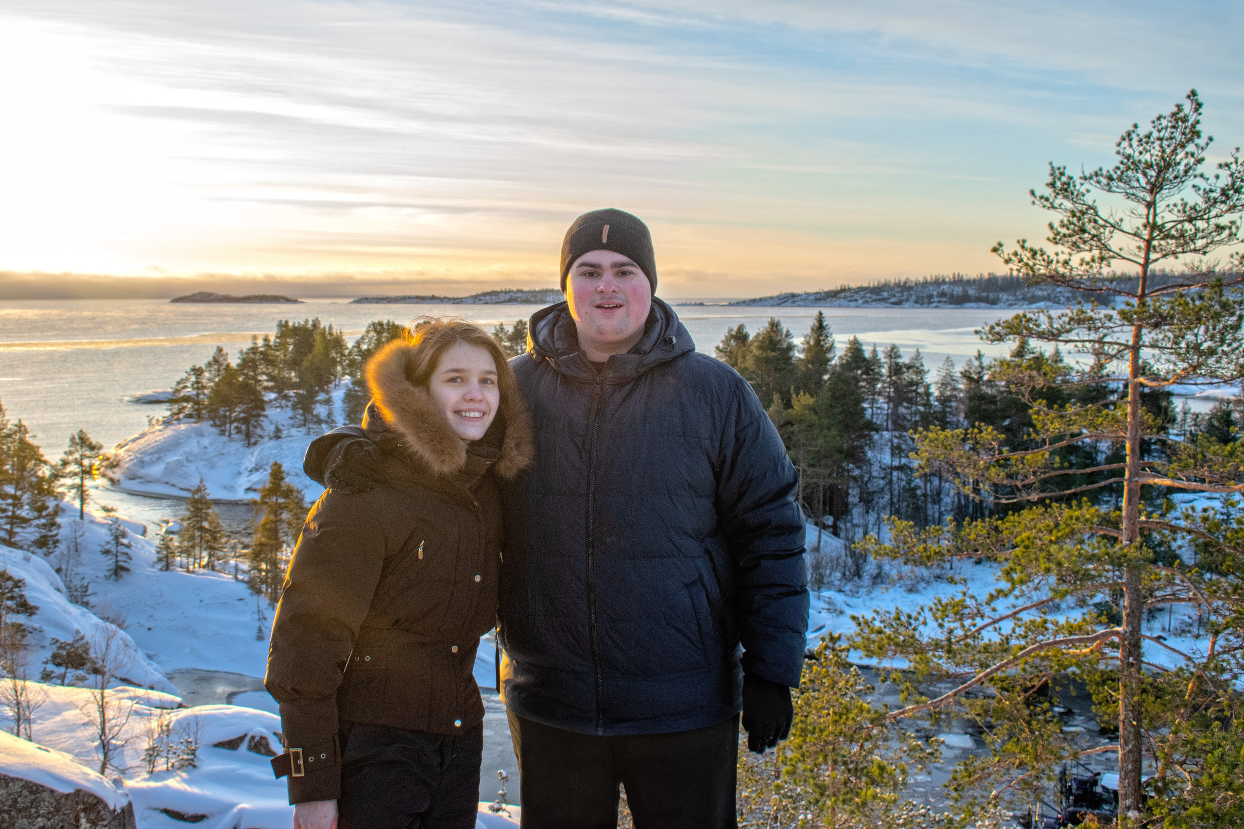 Фотосессия love story. Ладожские шхеры, Карелия. Пара стоит на фоне красивого зимнего пейзажа.