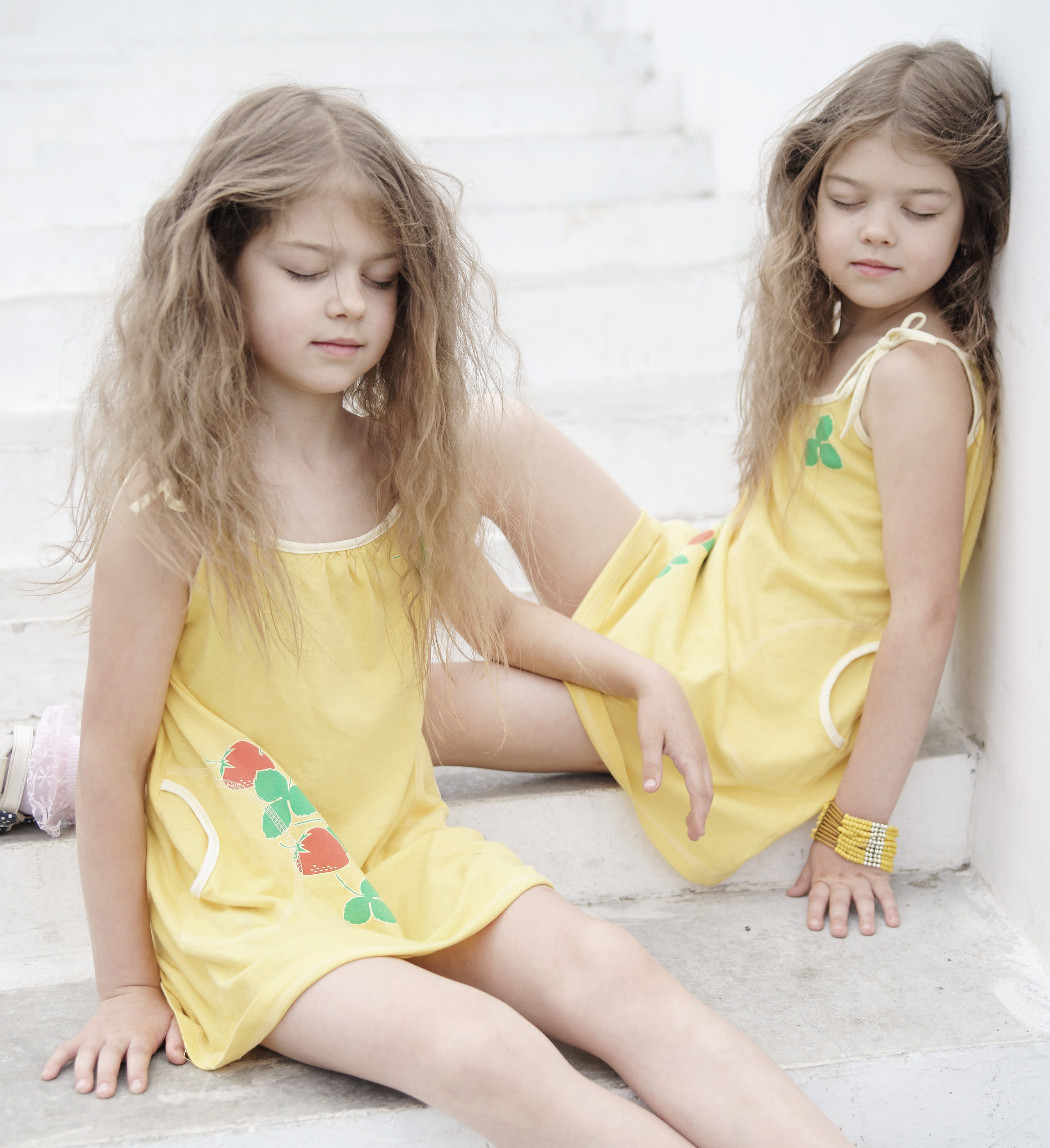 Детская фотосессия летом - сестры сидя на лестнице с закрытыми глазами