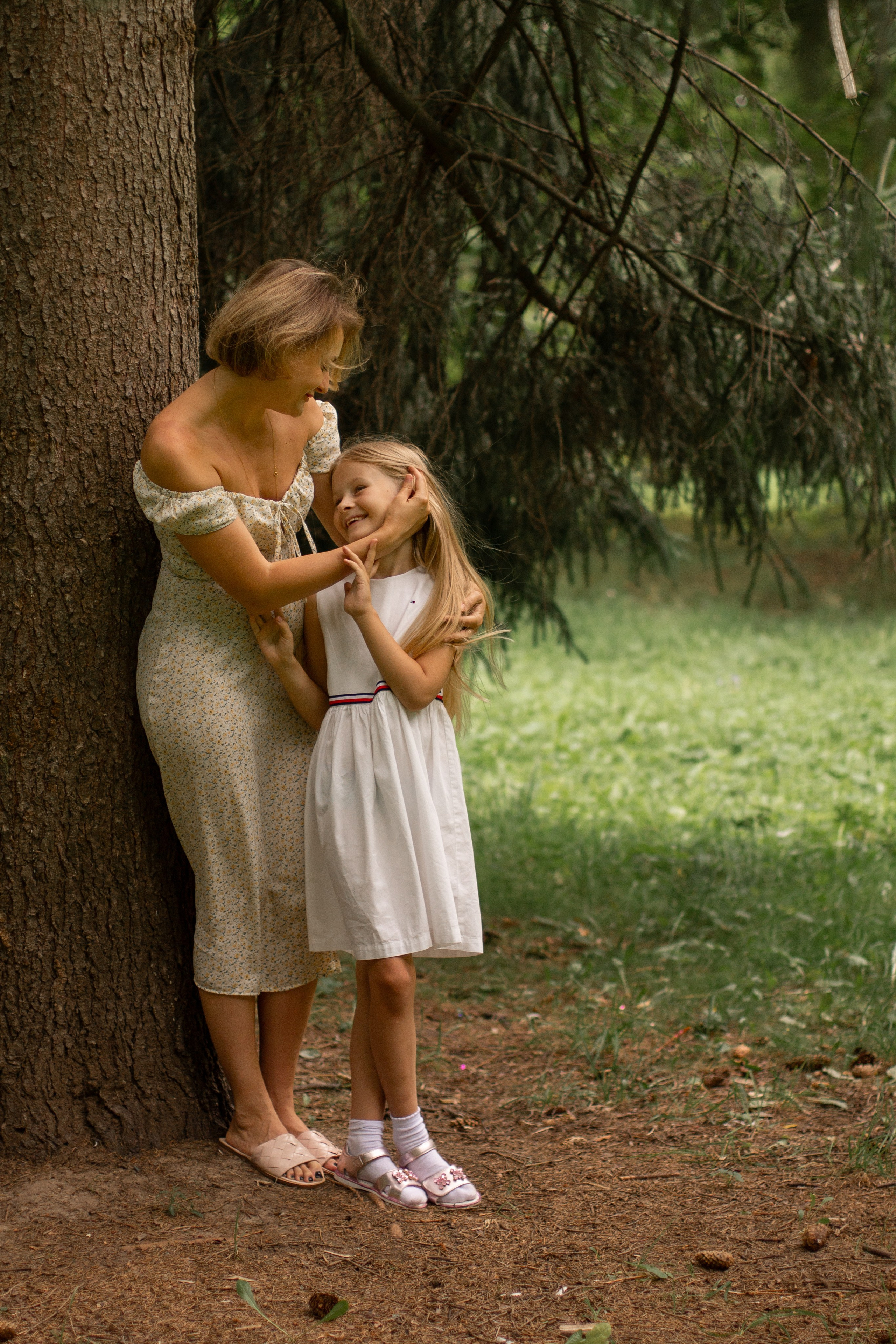 Мама и дочка стоят около дерева, семейная фотосессия летом