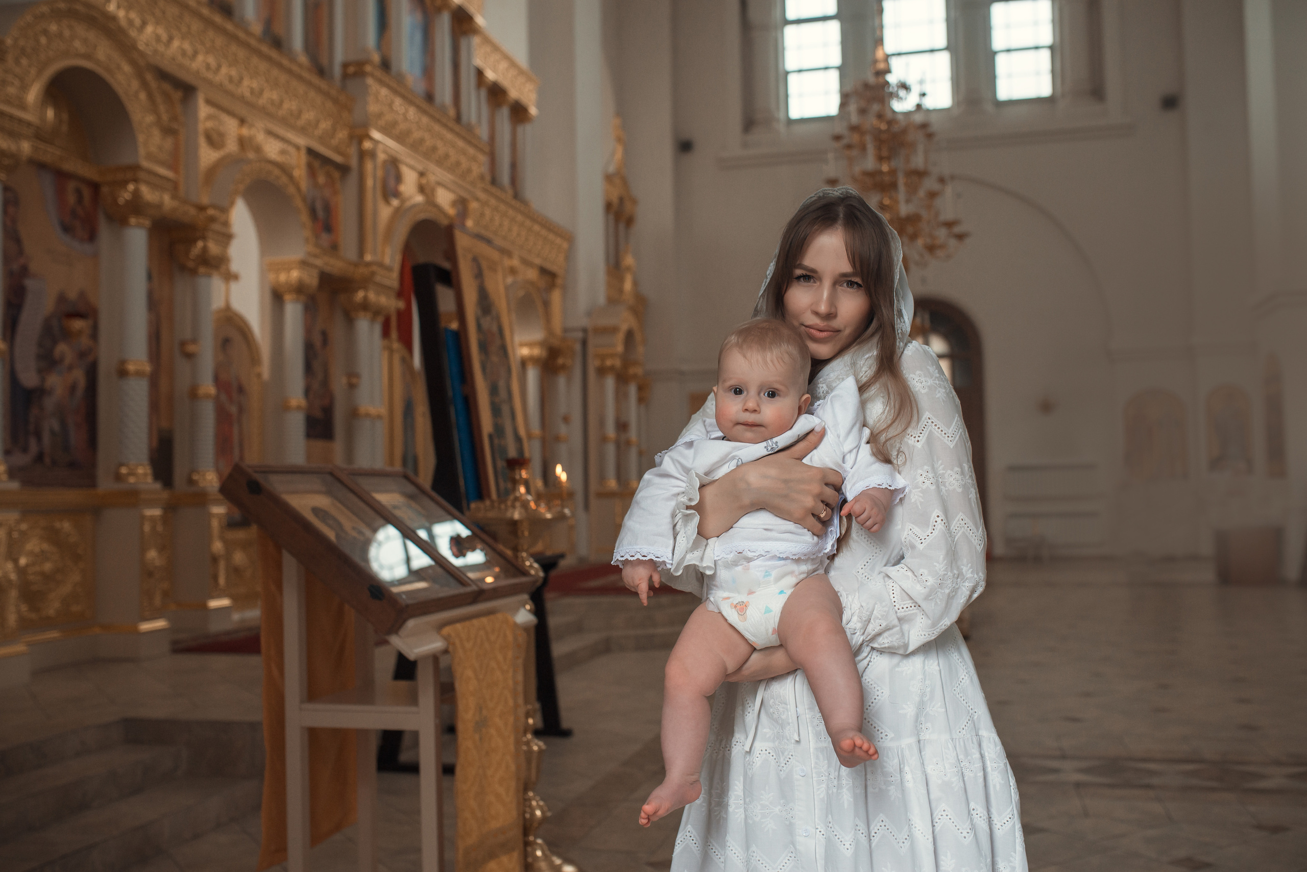 мама с малышом на руках после крещения