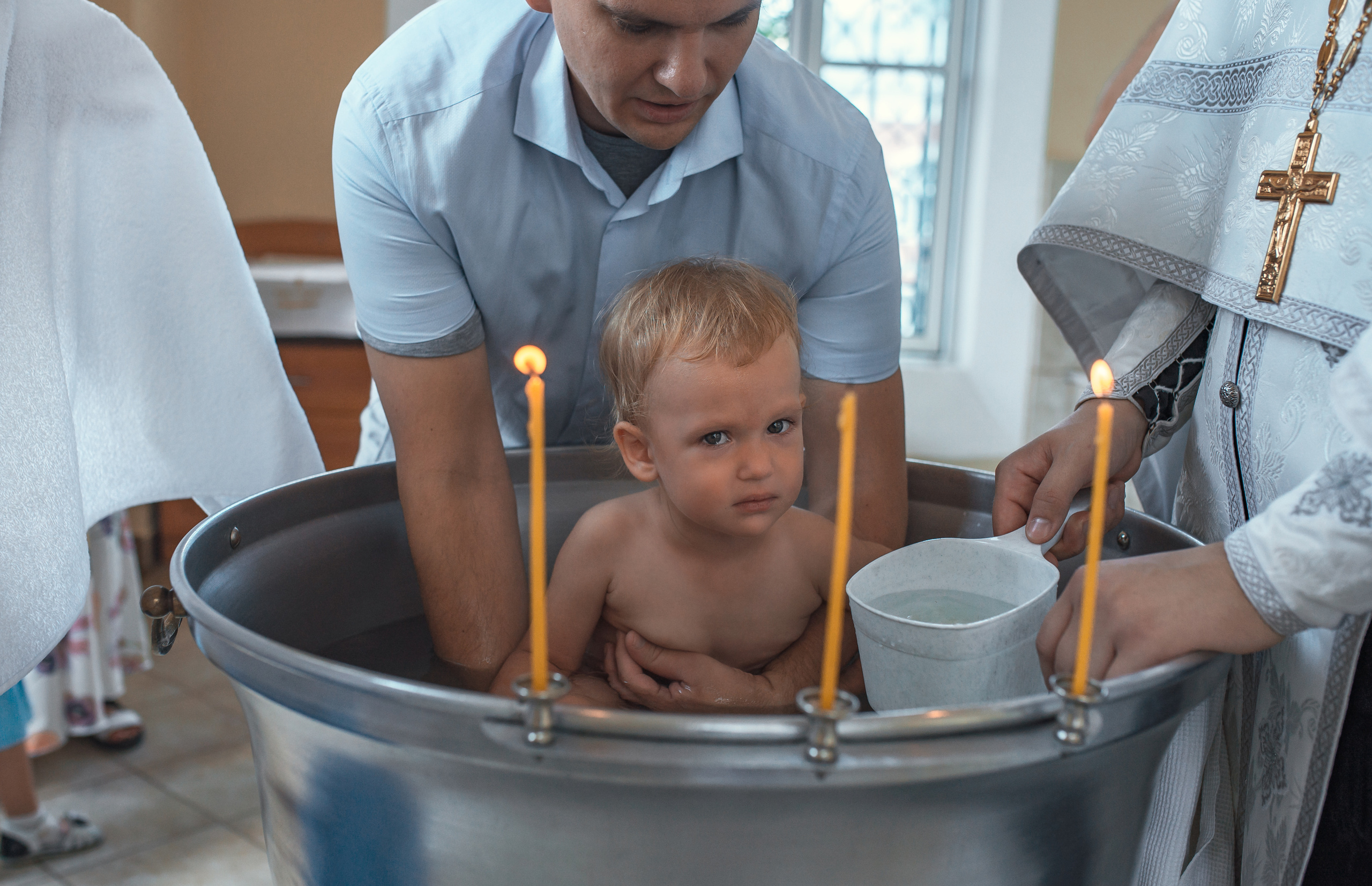 малыш в купели, батюшка крестит