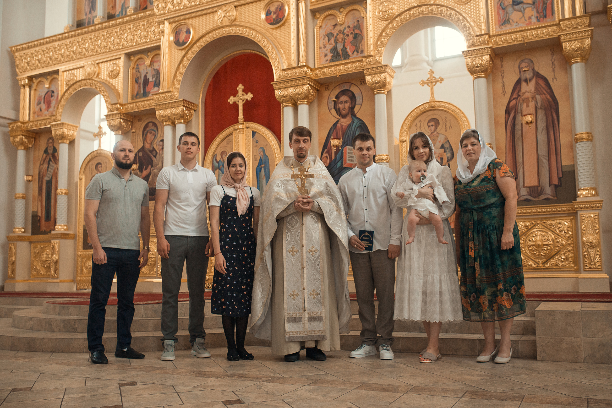 вся семья после крестин малыша на фоне алтаря