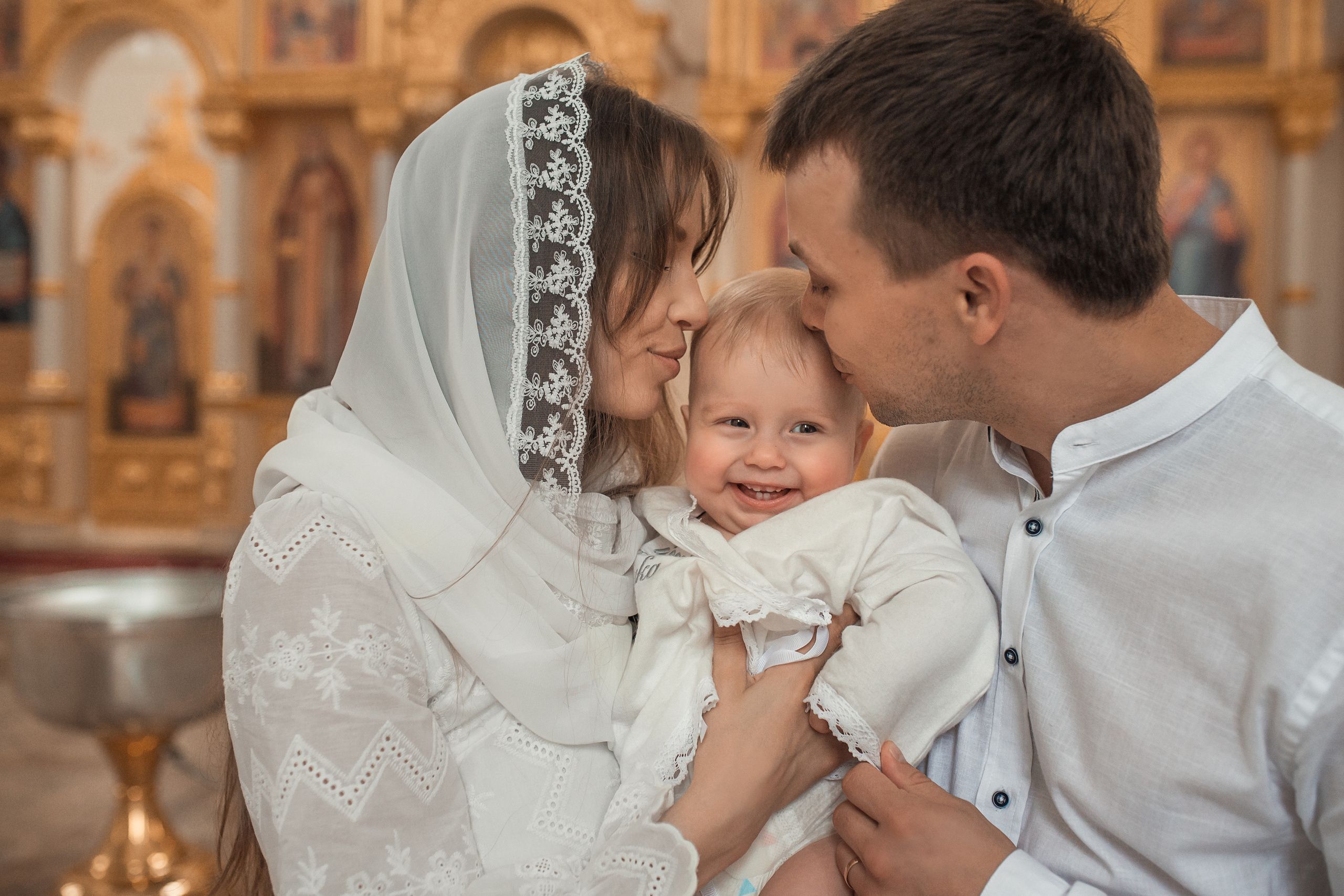 мама и папа целуют малыша