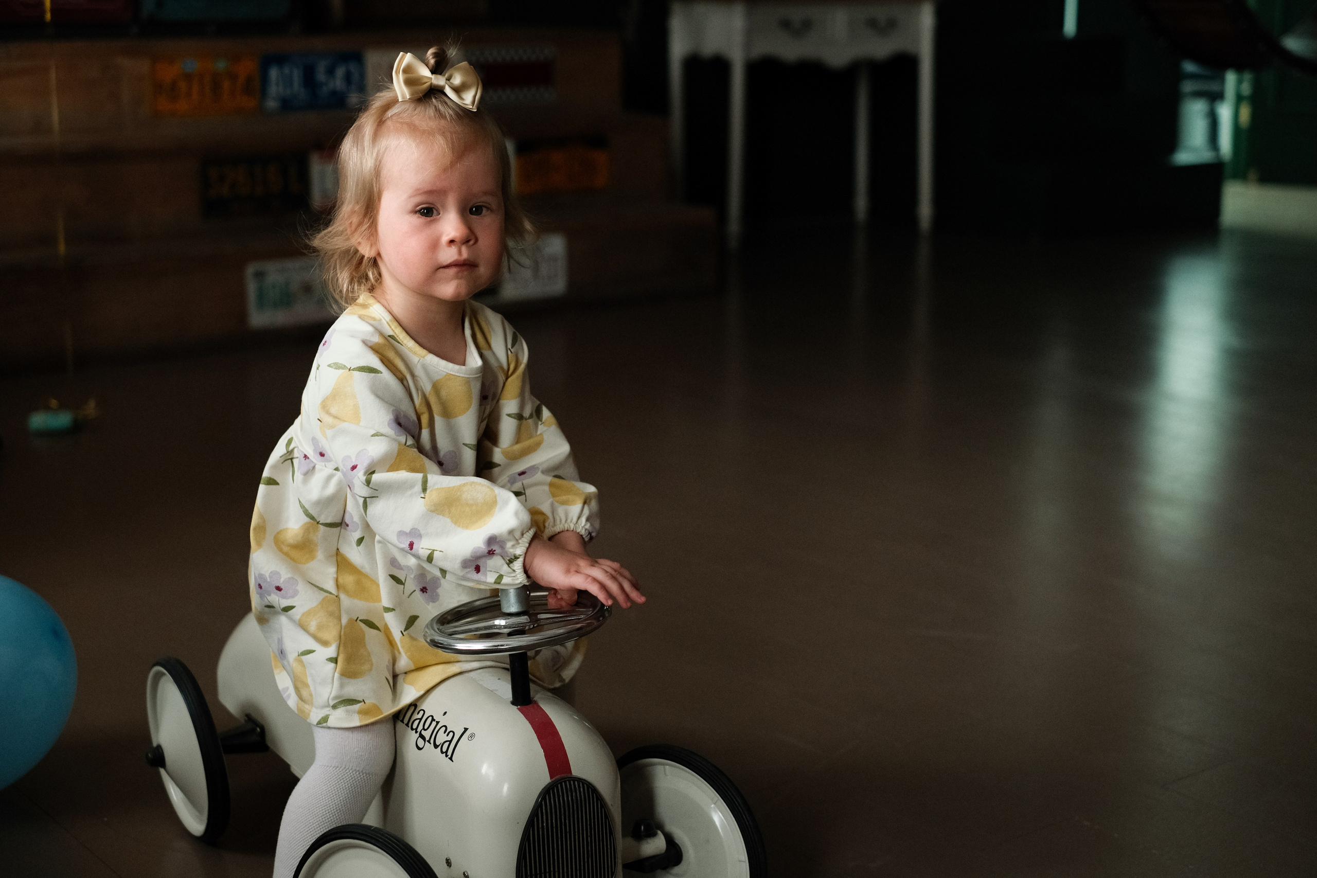 Маленькая девочка катается на игрушечной машине. 