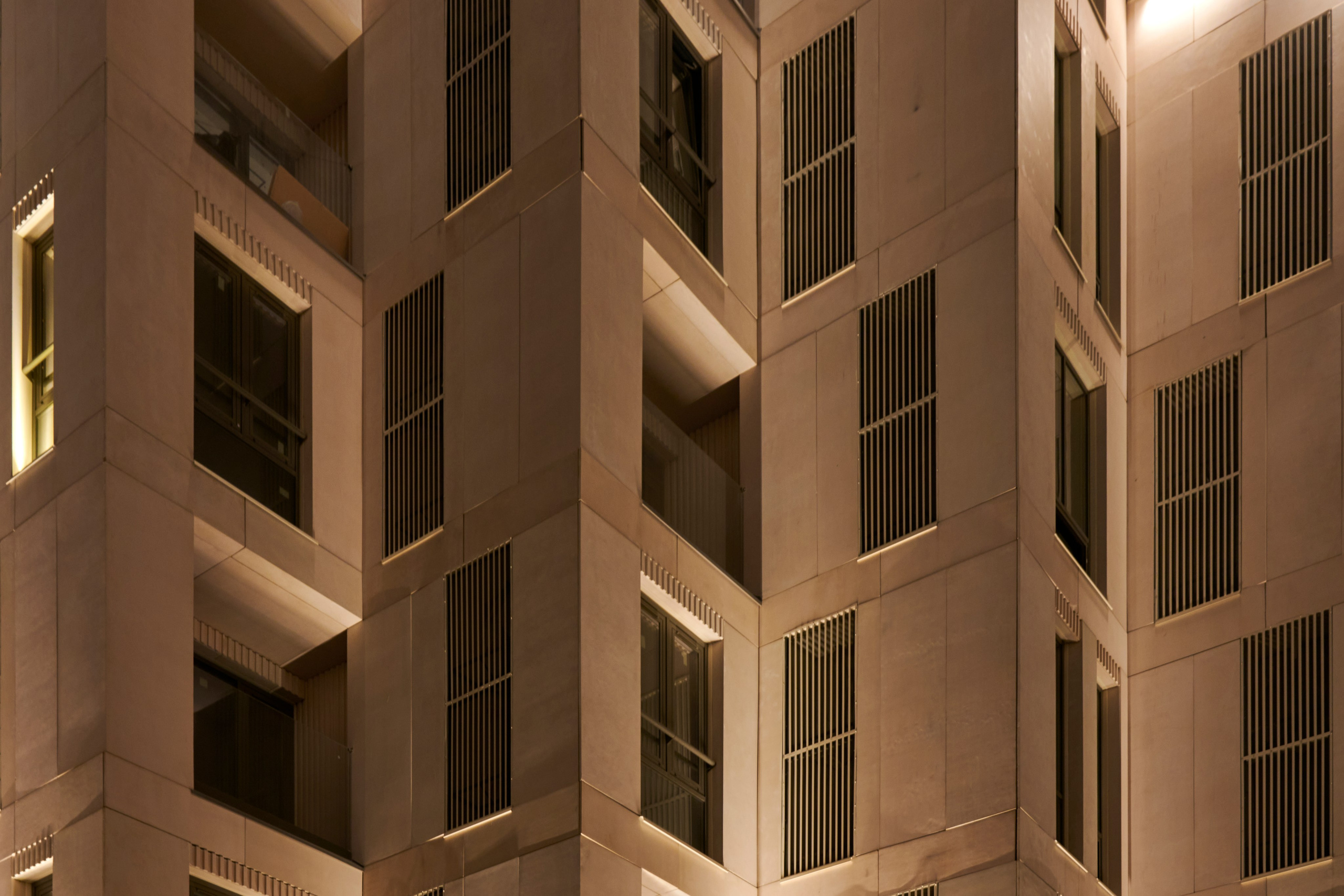 Крупный план фасада: вертикальные ниши и тёплые окна