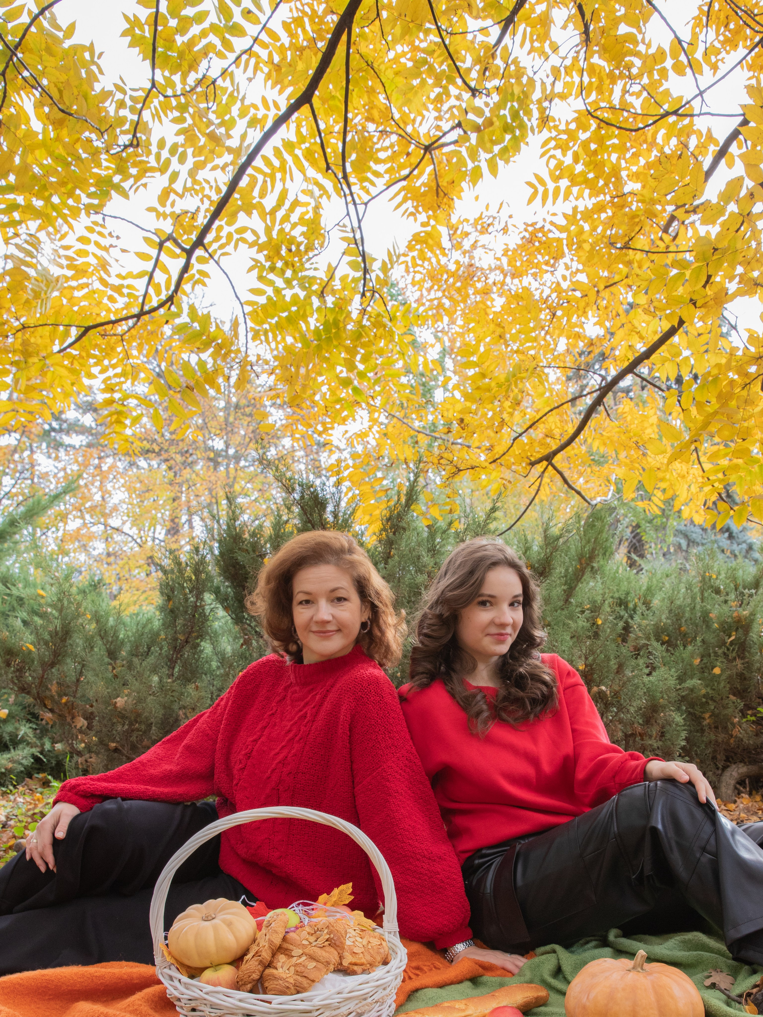 Мама с дочкой  улыбаются на фоне осенних  желтых деревьев в Чистяковской роще, яркие свитера  создают атмосферу уюта.