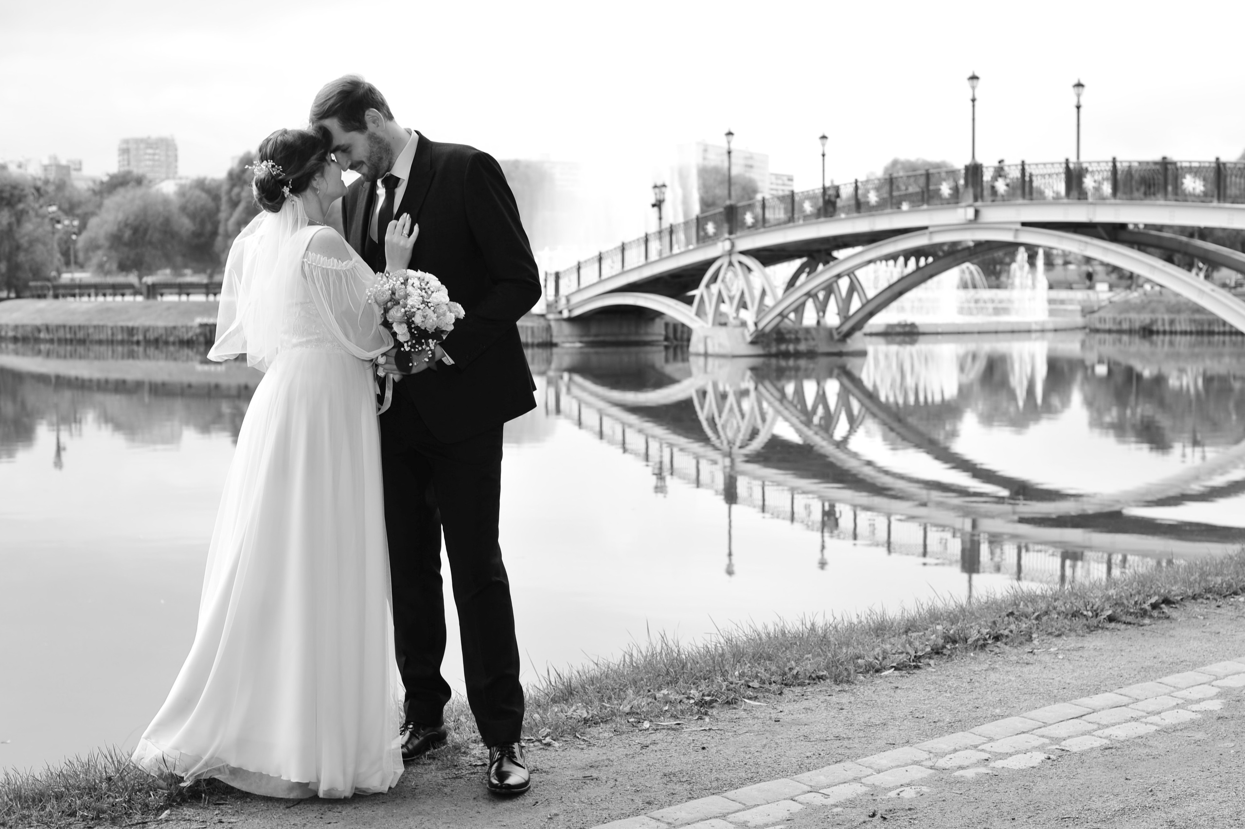 Свадьба в Царицыно пасмурным летним днем, новобрачные в полный рост на фоне пруда и моста в парке,  черно-белая фотография
