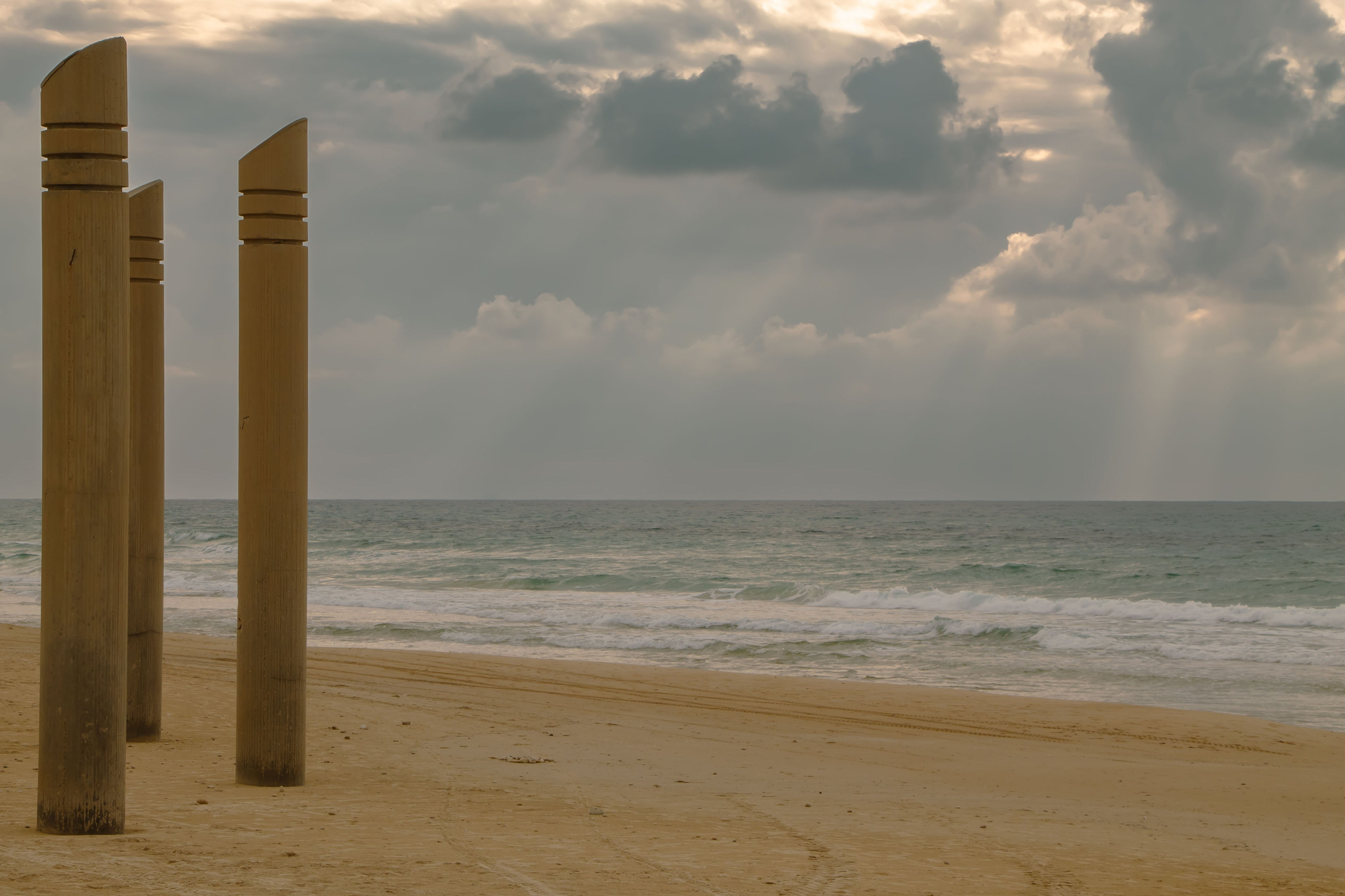 столбы на пляже, скульптуры возле моря, море и искусство