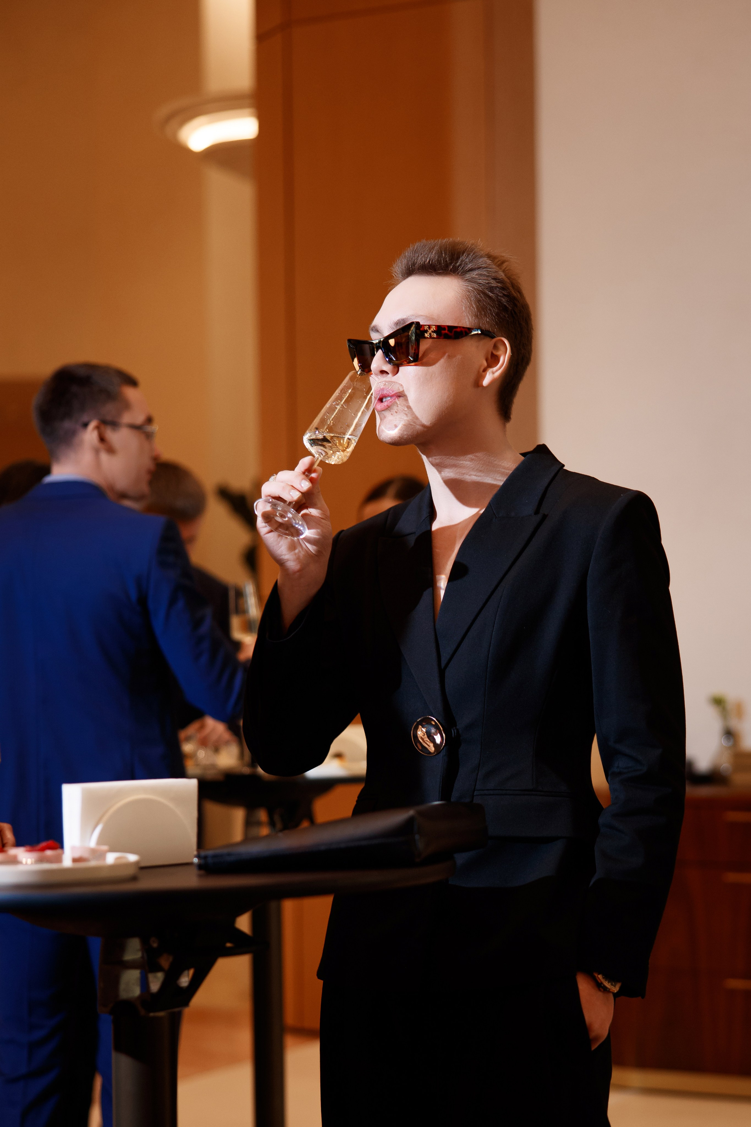 Стиль: Гость в черном костюме и солнцезащитных очках с бокалом шампанского на светском рауте.