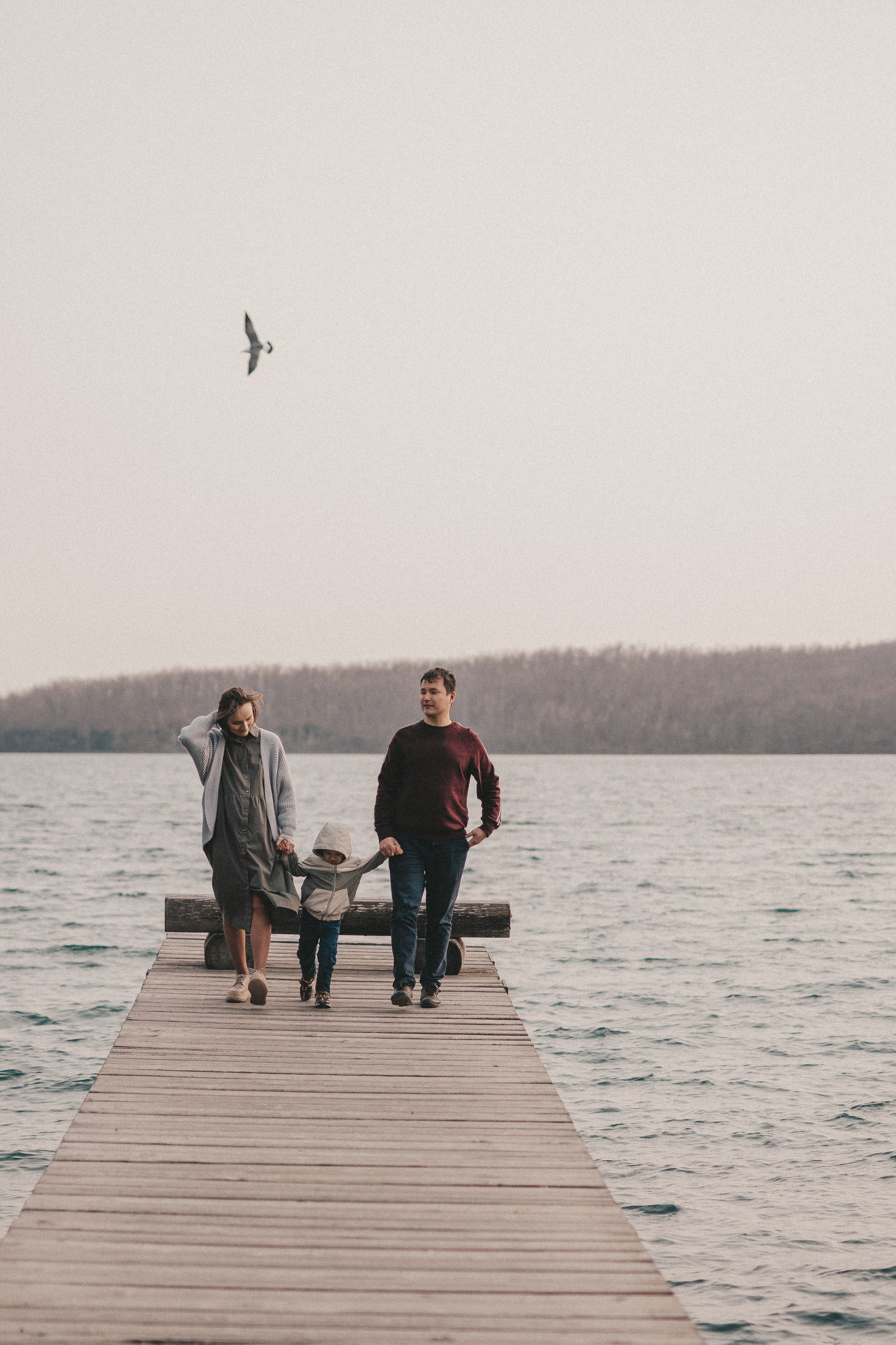 кадр семьи с ребенком издалека на пирсе у моря