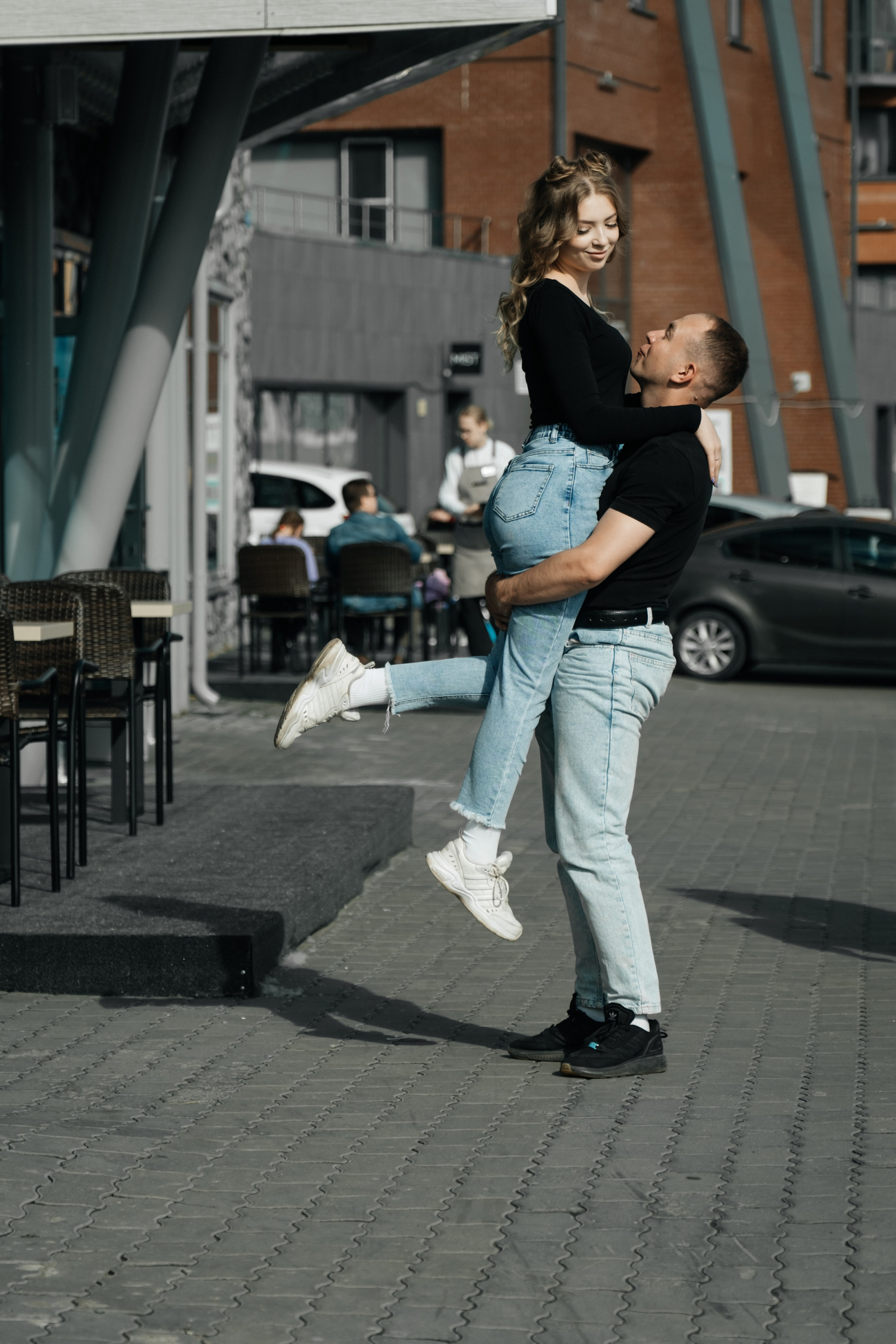 Молодая пара мужчина и девушка обнимаются городских локациях в черных футболках и синих джинсах, лав стори для влюбленной пары на кануне свадьбы