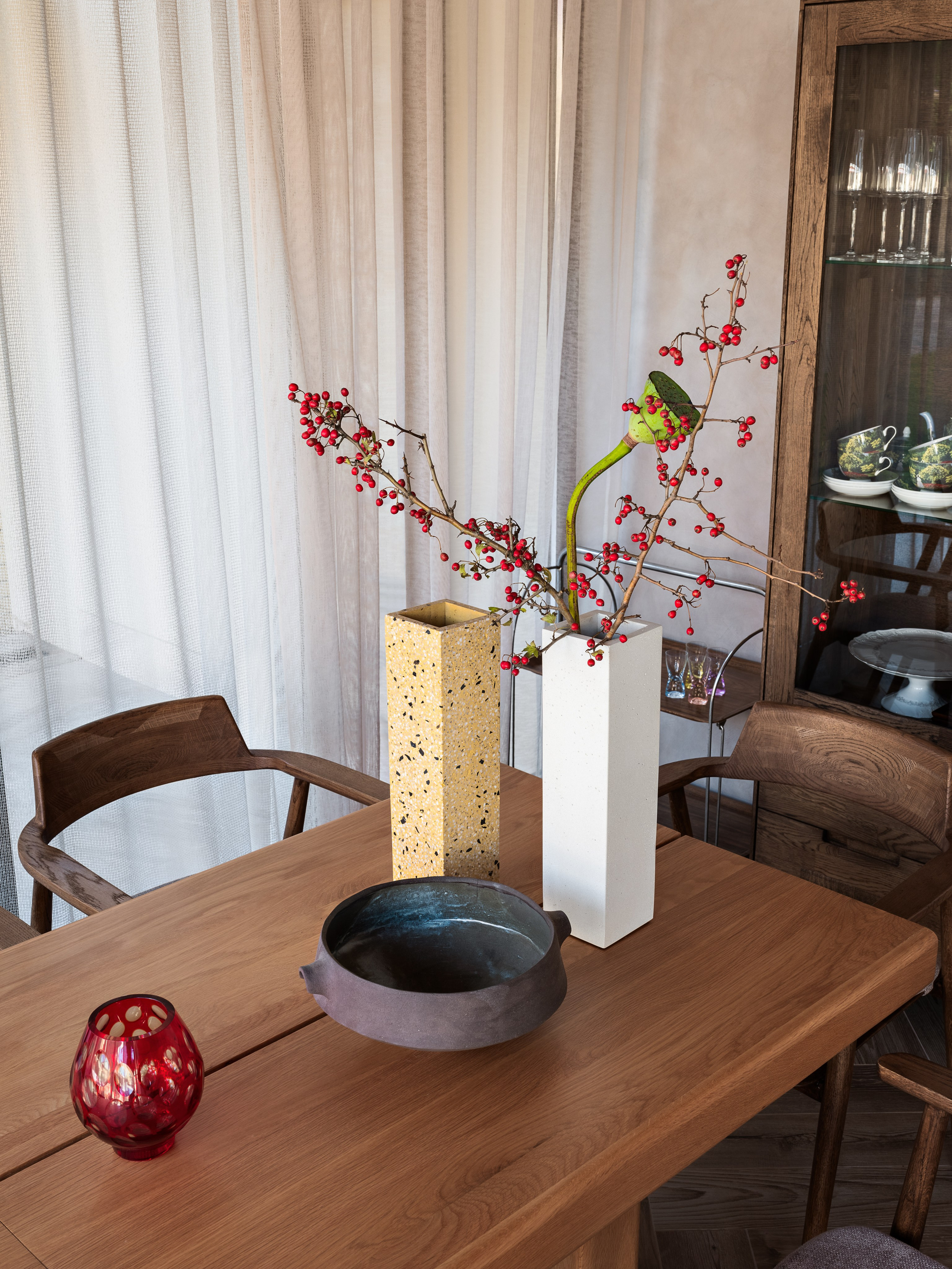 Детали интерьера столовой — деревянный стол с керамической вазой, сухоцветами и красным подсвечником, создающими акценты в современном дизайне; автор проекта Наталия Шелепникова, стилист София Калбазова, фотограф Сергей Денисенко.