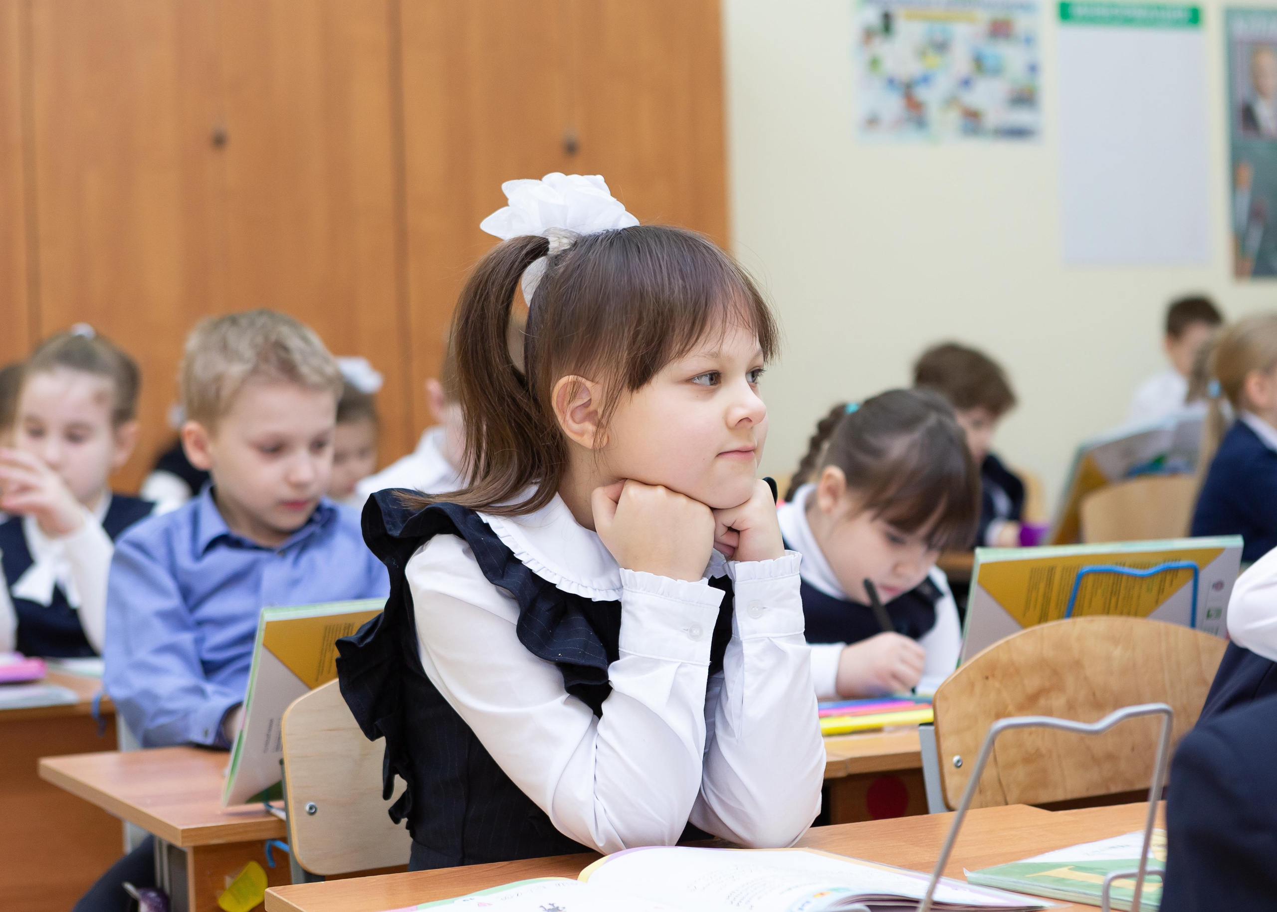 Девочка слушает учителя за партой