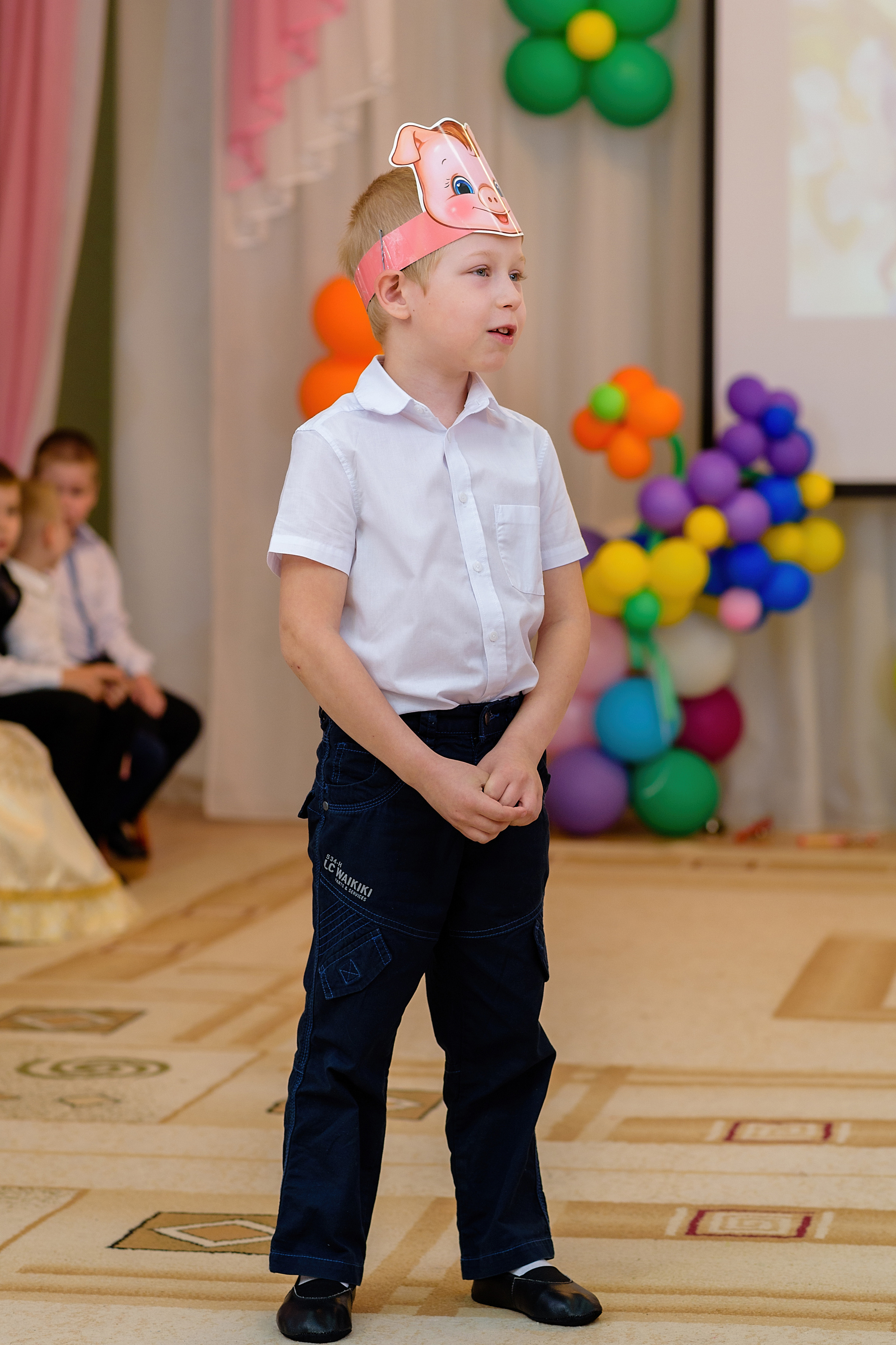 Мальчик на выпускном утреннике с шапочкой поросёнка показывает сценку