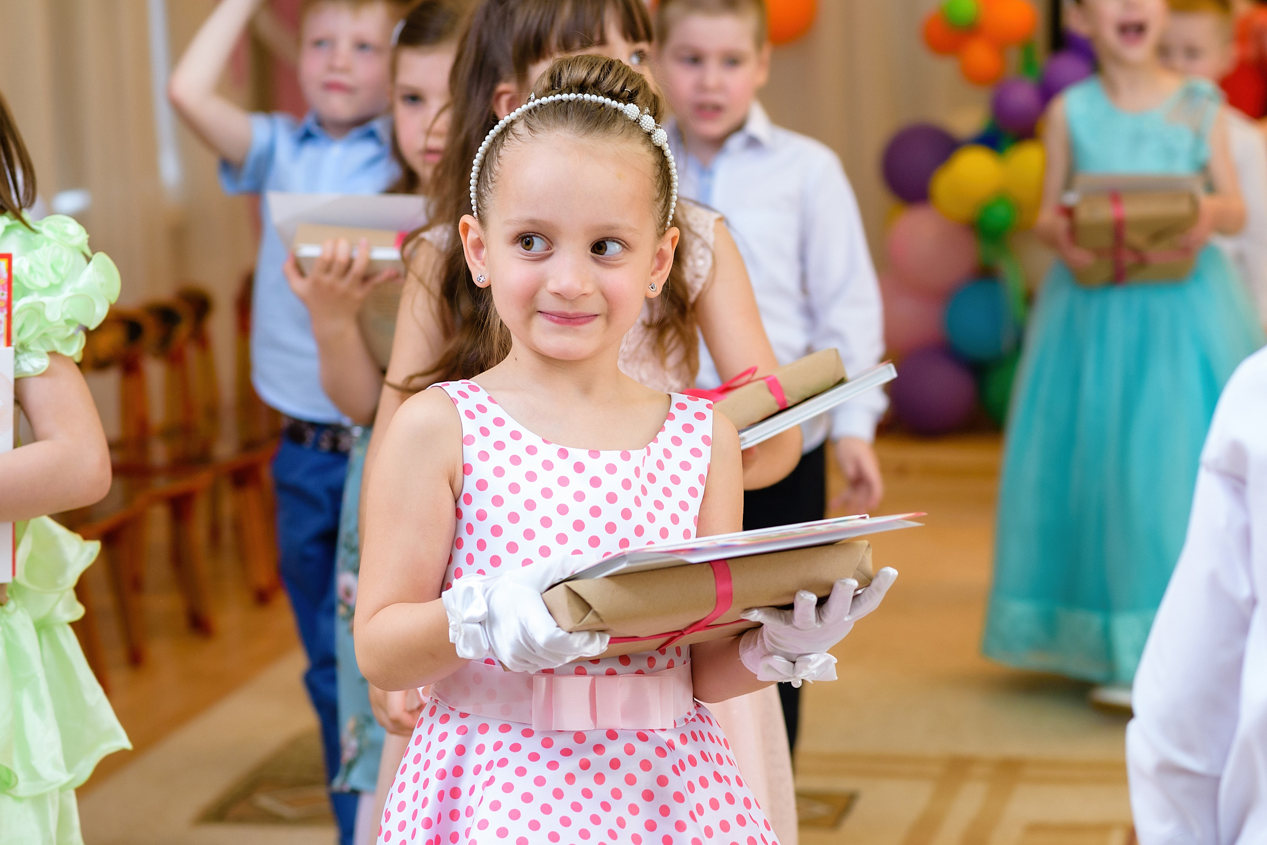 Выпускница из детского сада держит подарки и улыбается