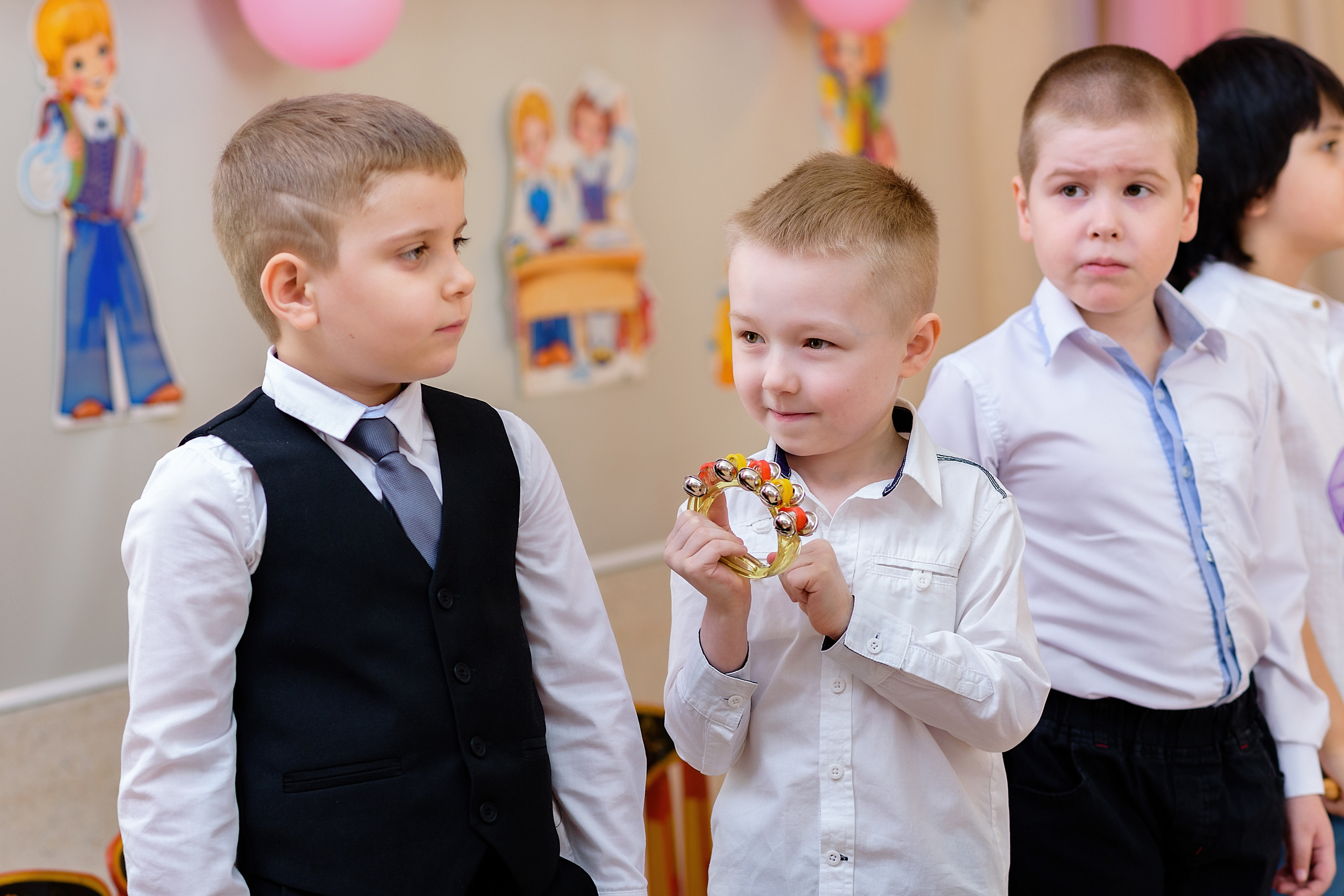 На выпускном из детского сада мальчик показывает бубен другим детям