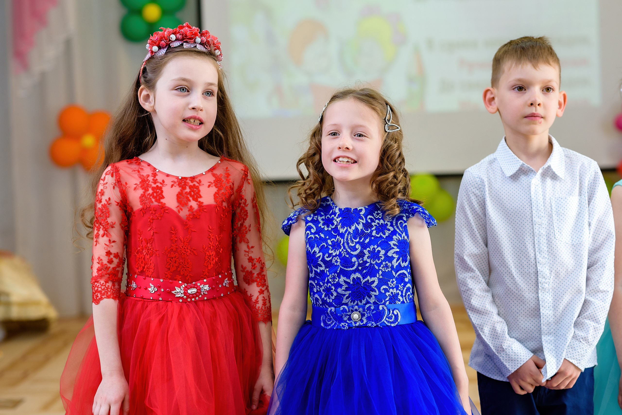 Две девочки и мальчик поют песню на выпускном из детского сада