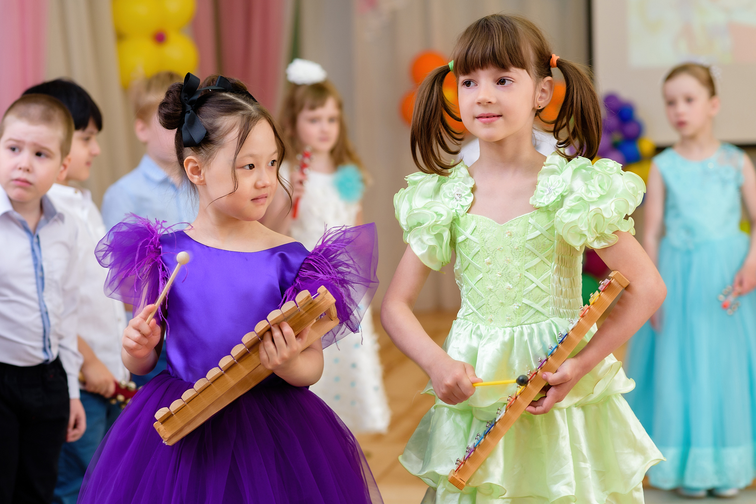 Две девочки играют на ксилофонах на выпускном из детского сада