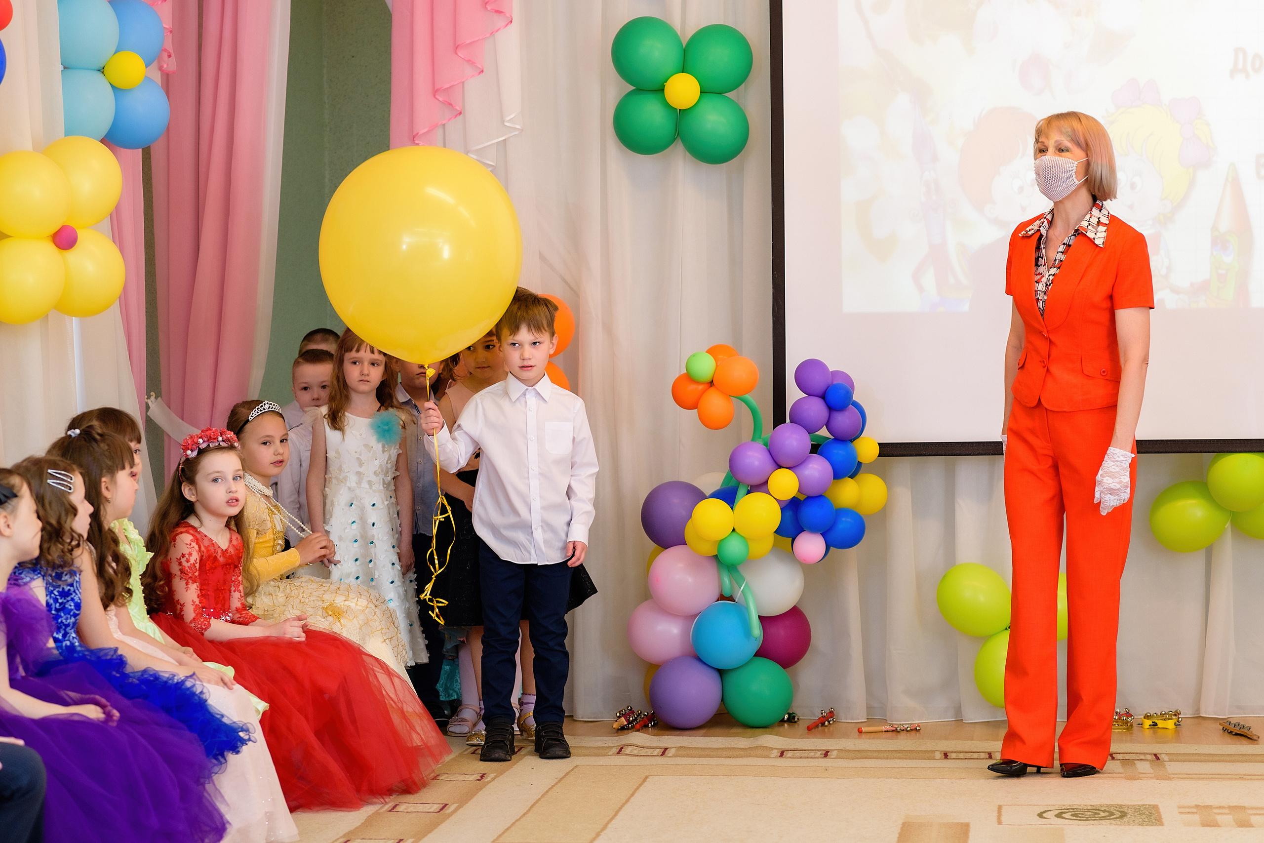 На выпускном из детского сада мальчик держит огромный жёлтый шар