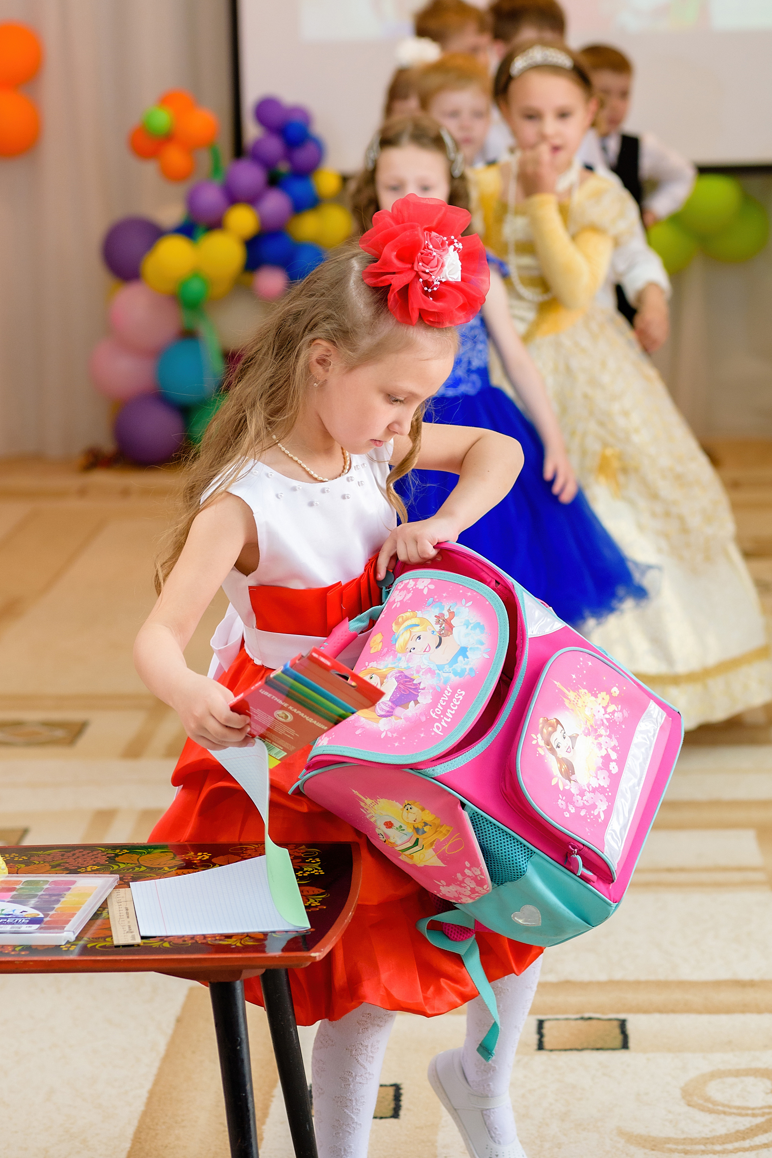 Девочка участвует в конкурсе на выпускном празднике. Она складывает вещи в портфель