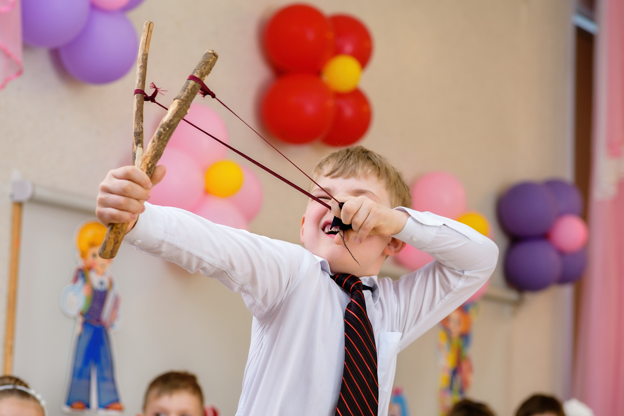 Мальчик на выпускном участвует в сценке, он натянул рогатку