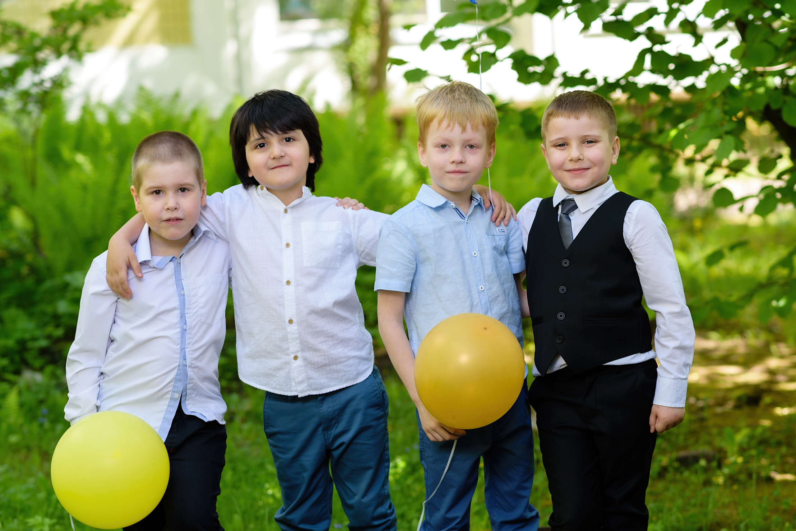 Четыре выпускника из детского сада стоят на улице и держат шарики