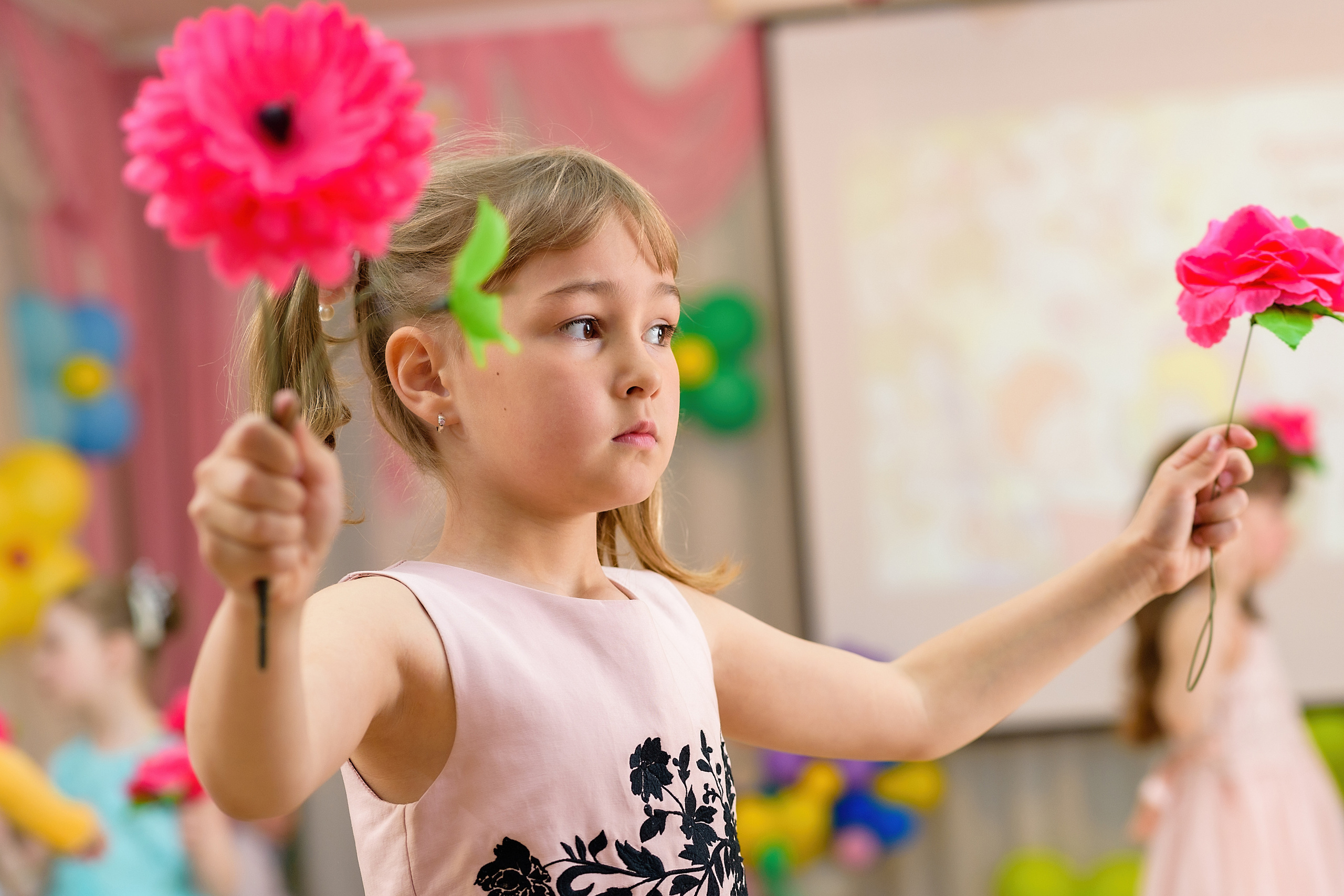 Девочка танцует с цветами на выпускном из детского сада