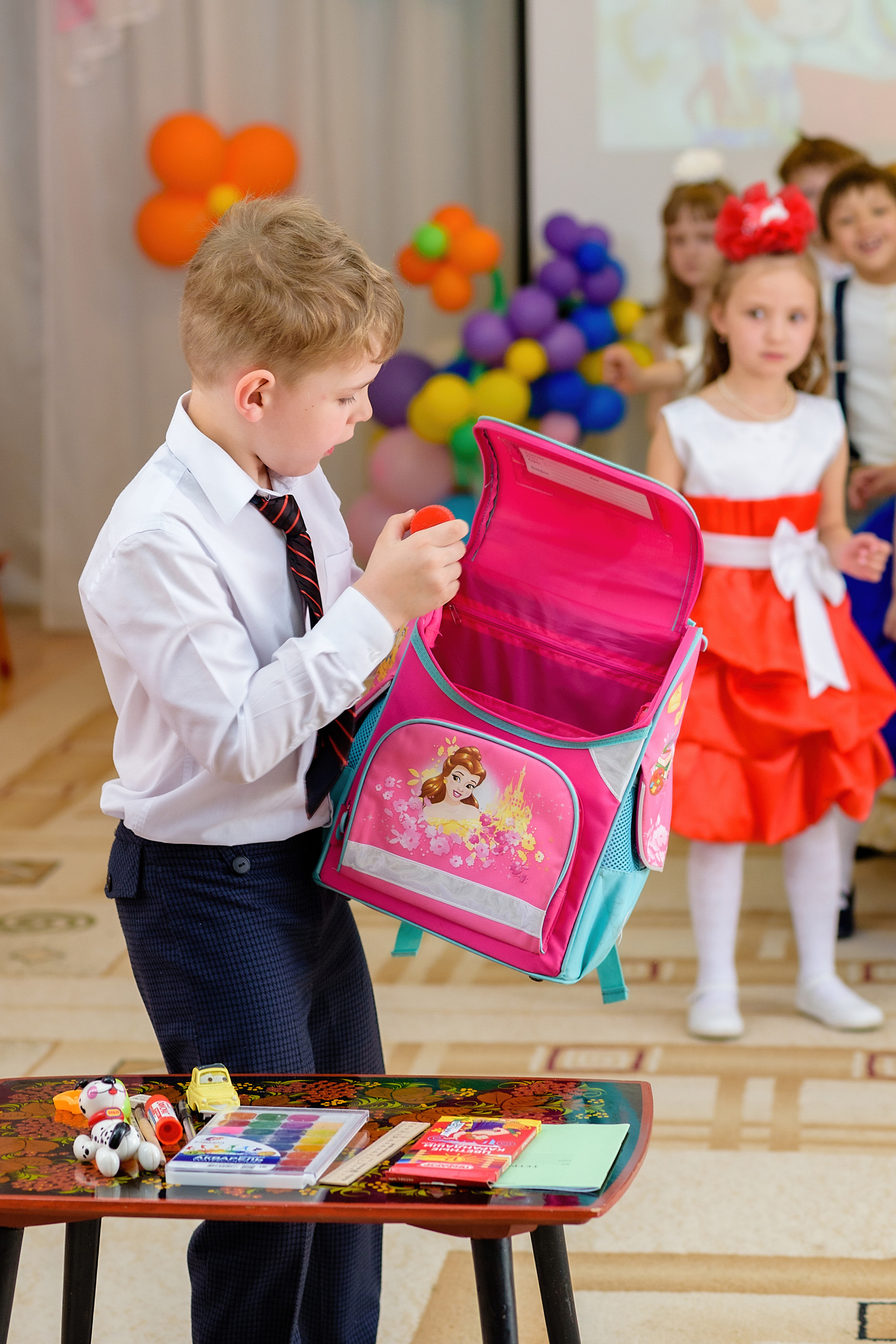 Мальчик на скорость собирает портфель во время выпускного утренника