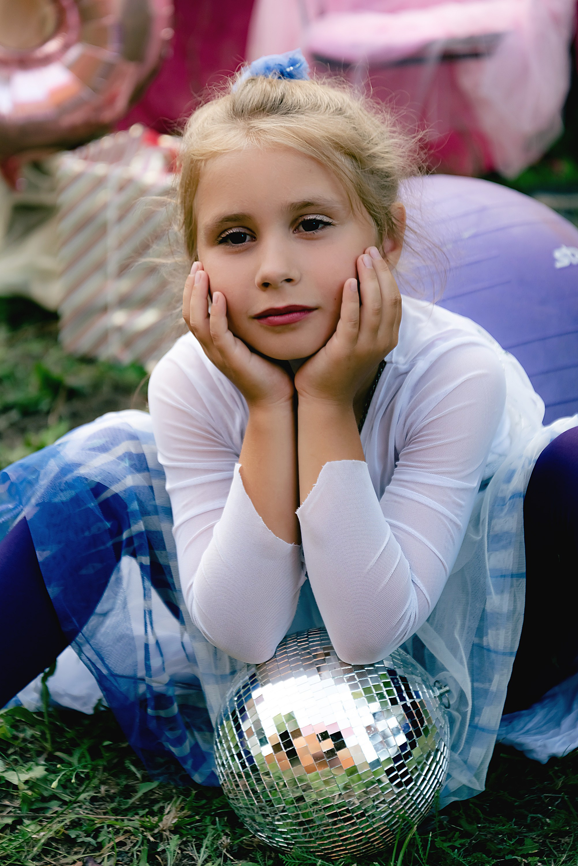 На фото девочка сидит облокотившись на шарик.