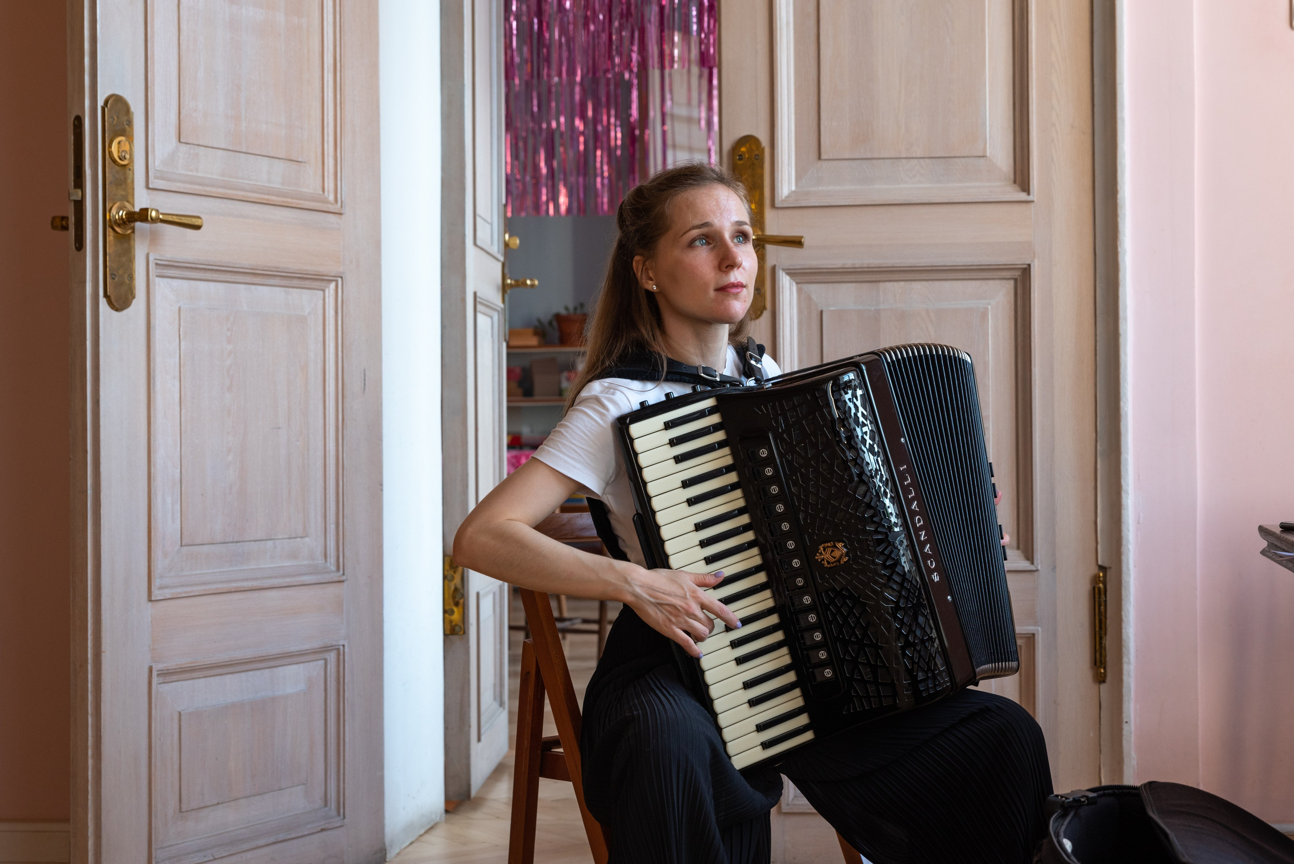 Девушка играет на аккордеоне на фоне старинной двери.