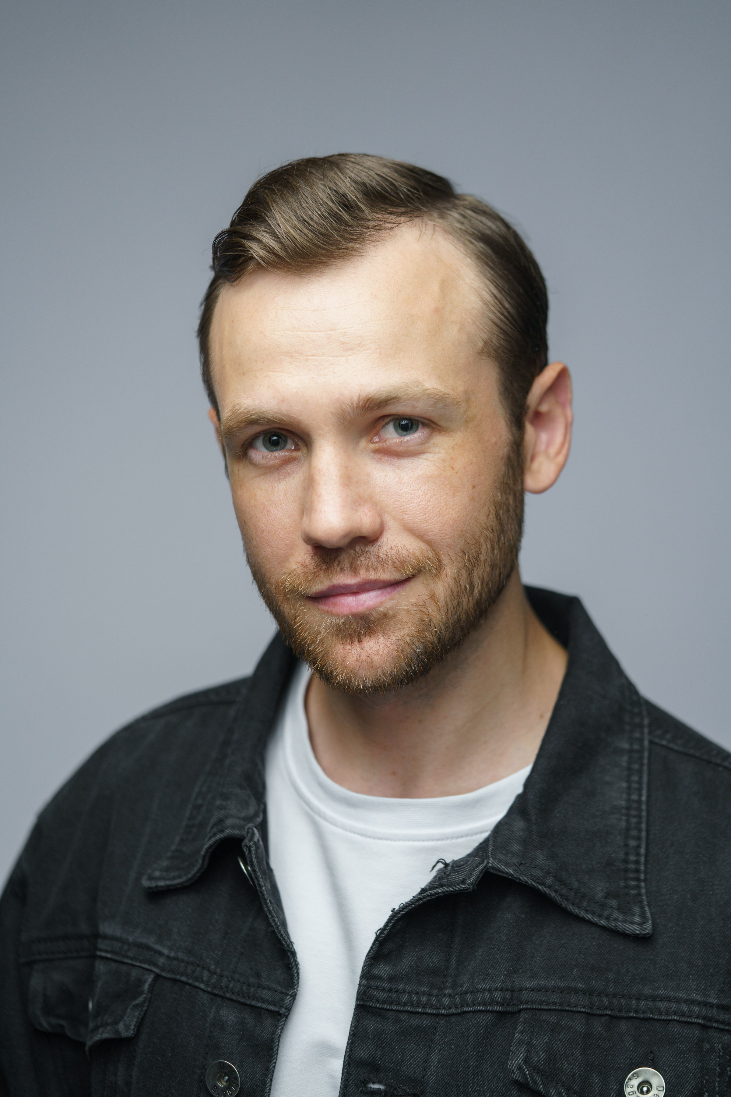 Портрет мужчины с короткой бородой в черной джинсовой куртке