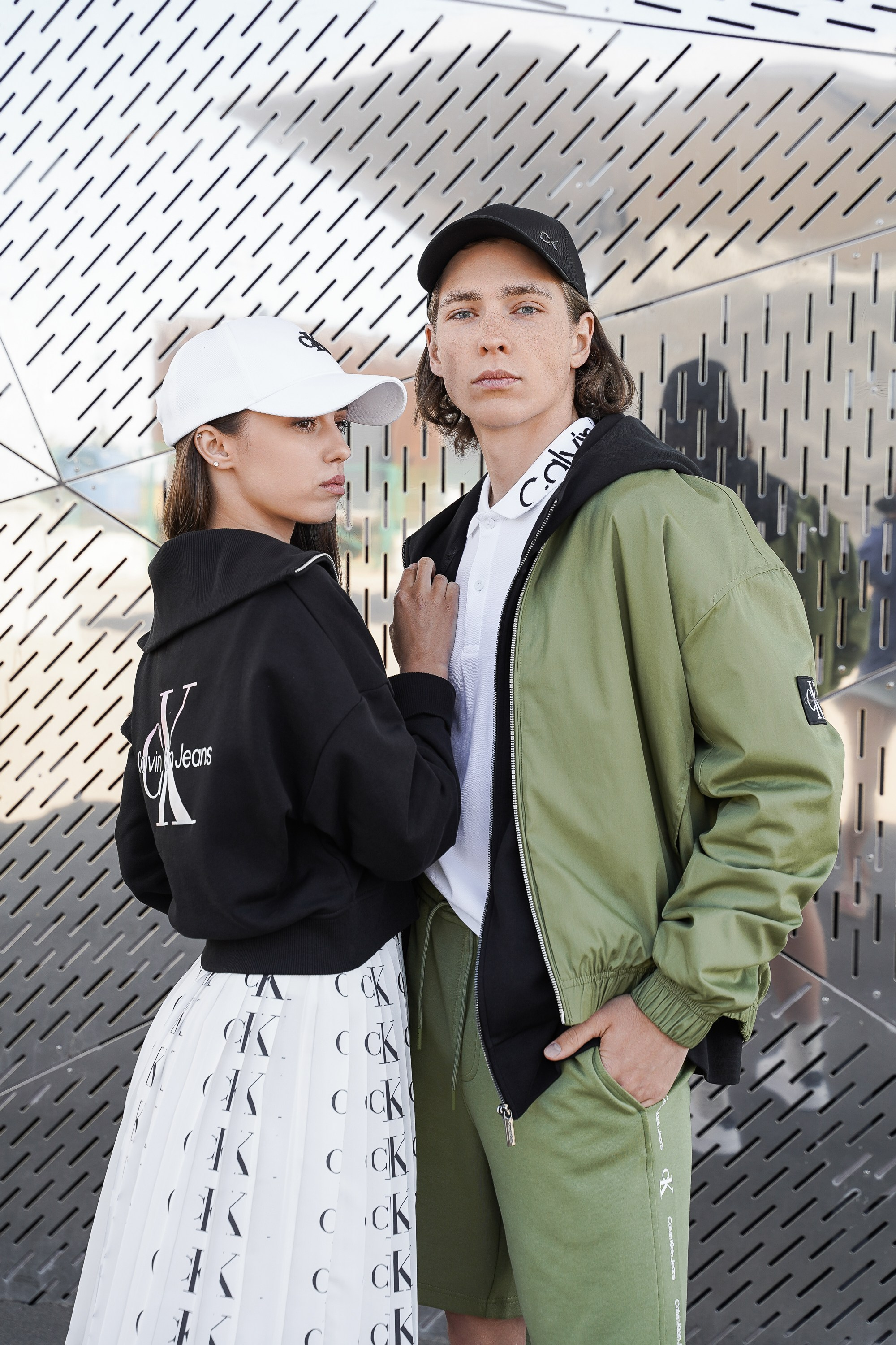 Девушка и парень в бейсболках рекламируют одежду