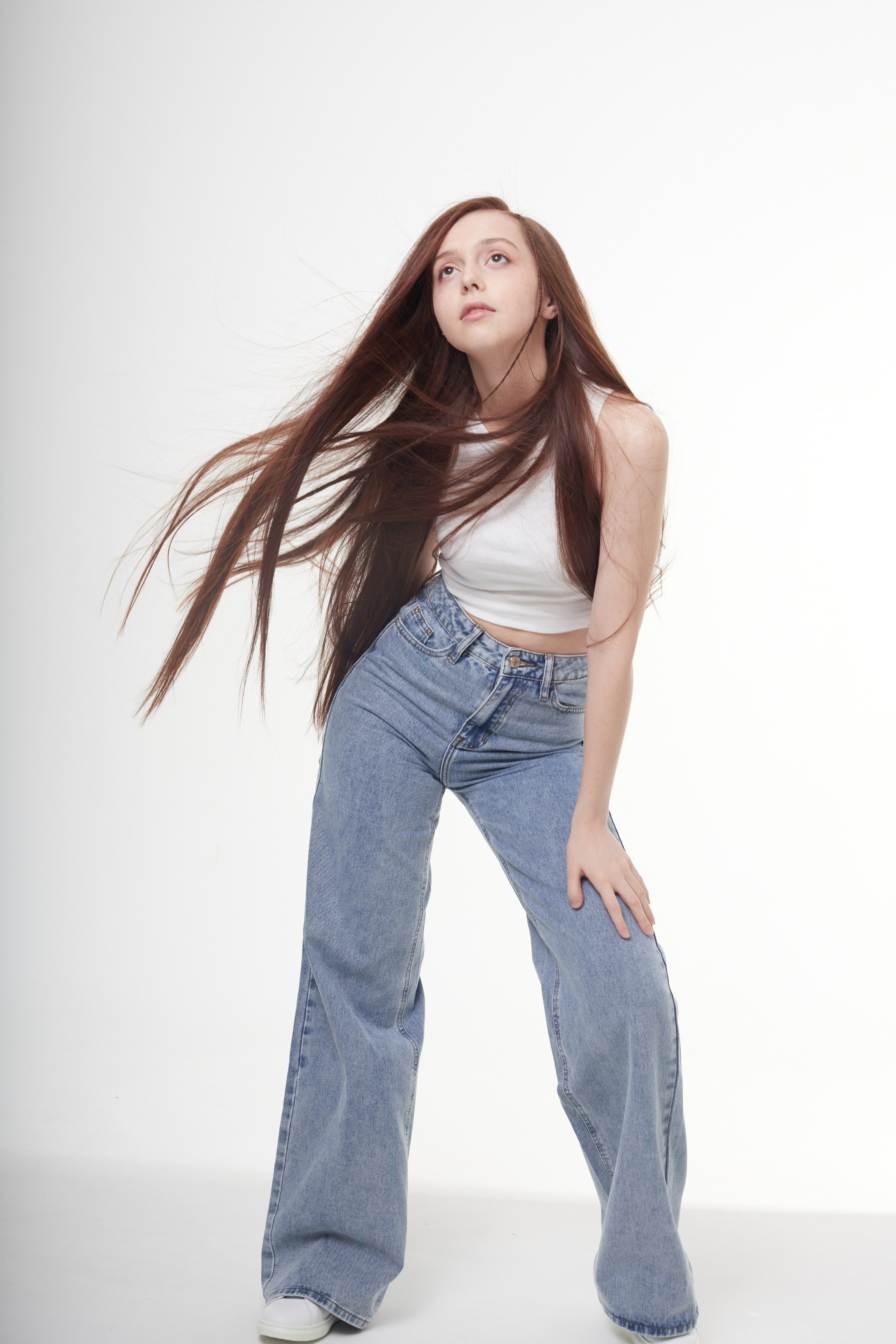 Студийная съёмка девушки с длинными каштановыми волосами на белом фоне.