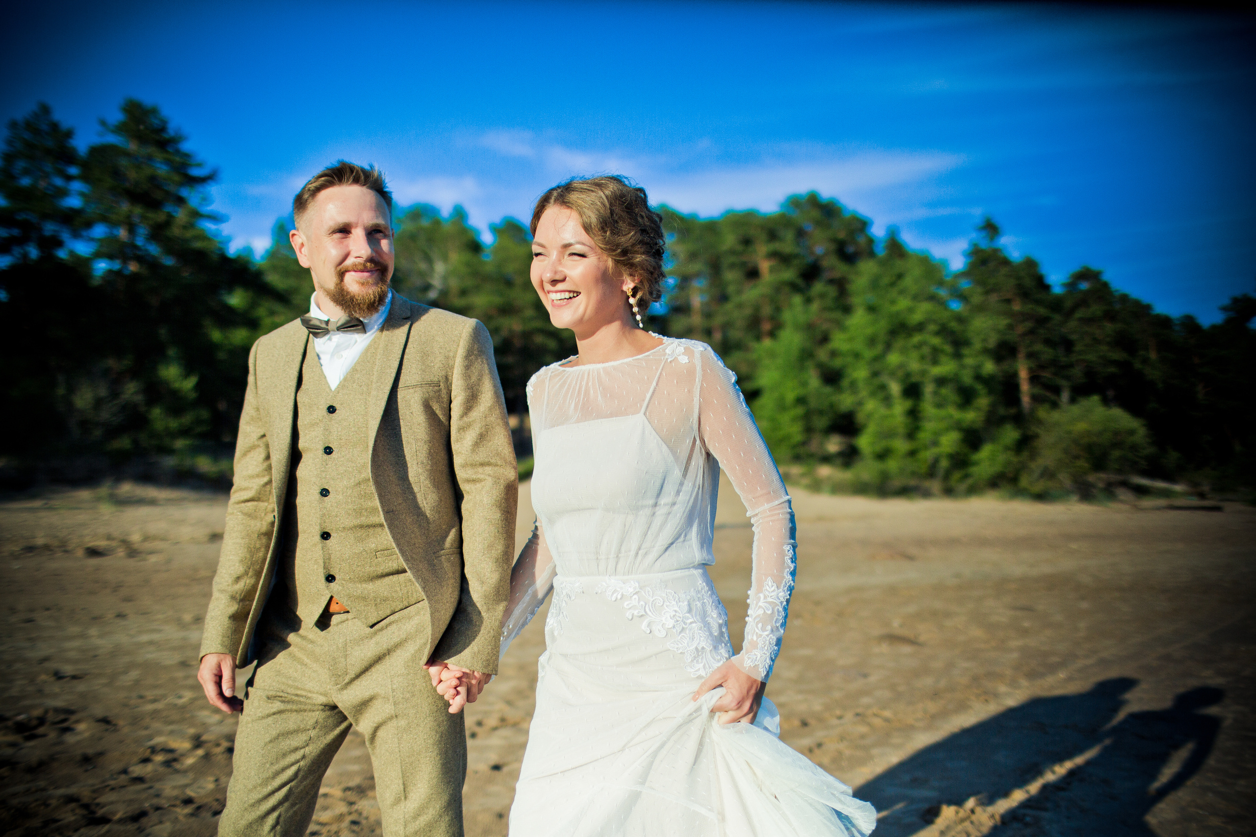 невеста и жених в ретро стиле взявшись за руке на пляже залива