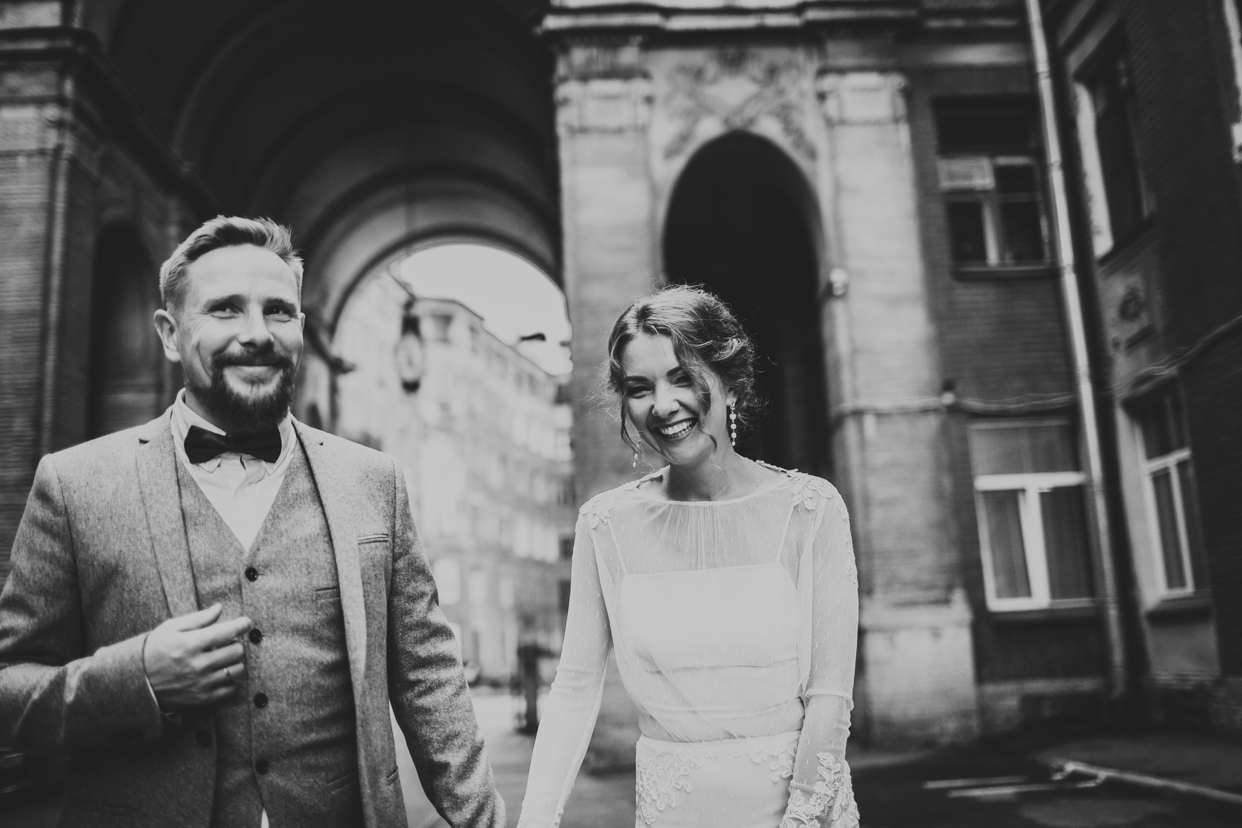 жених держит за руку смеющуюся невесту во дворе толстовского дома на фонтанке