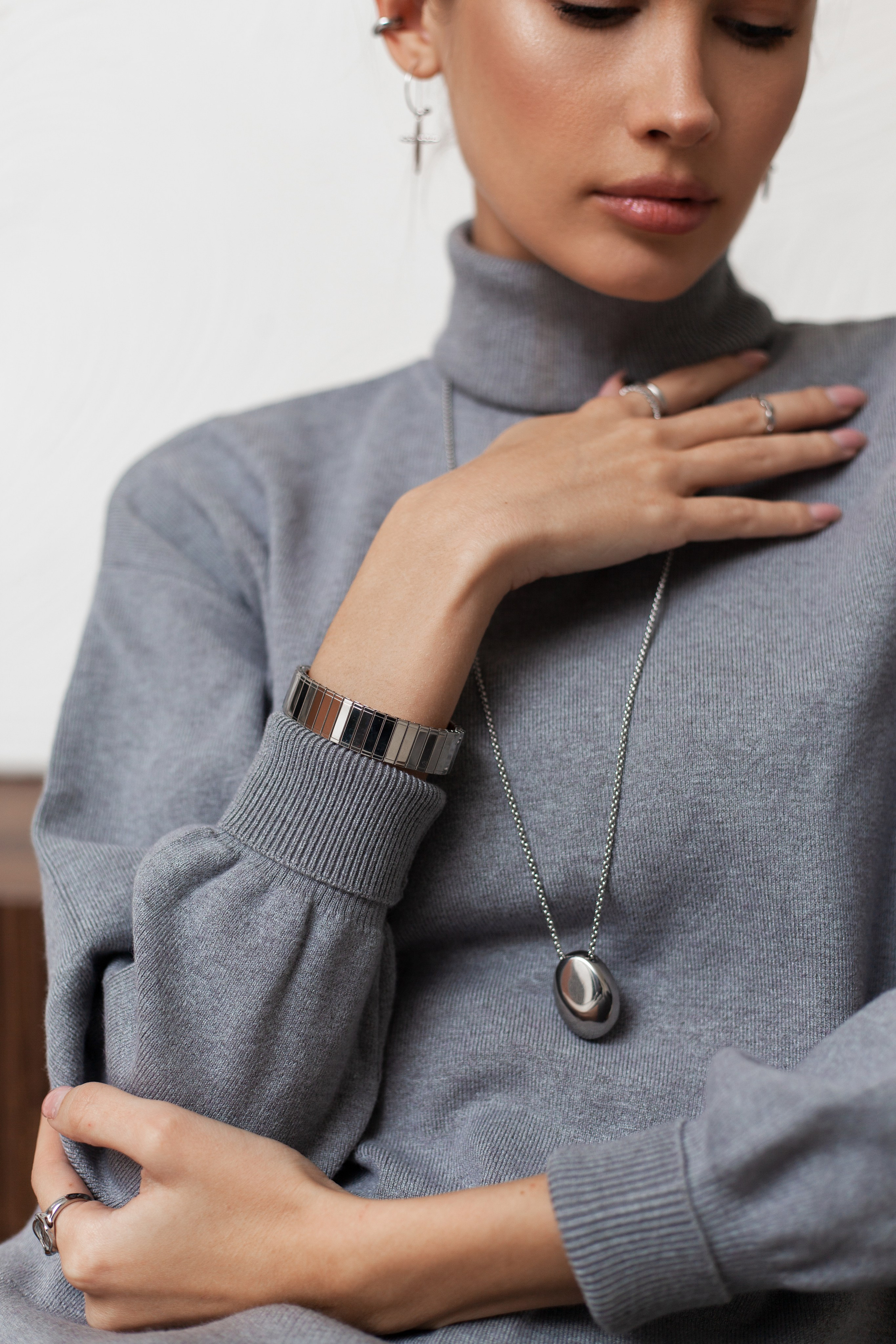 Девушка в сером свитере с браслетом с в студии на белом фоне