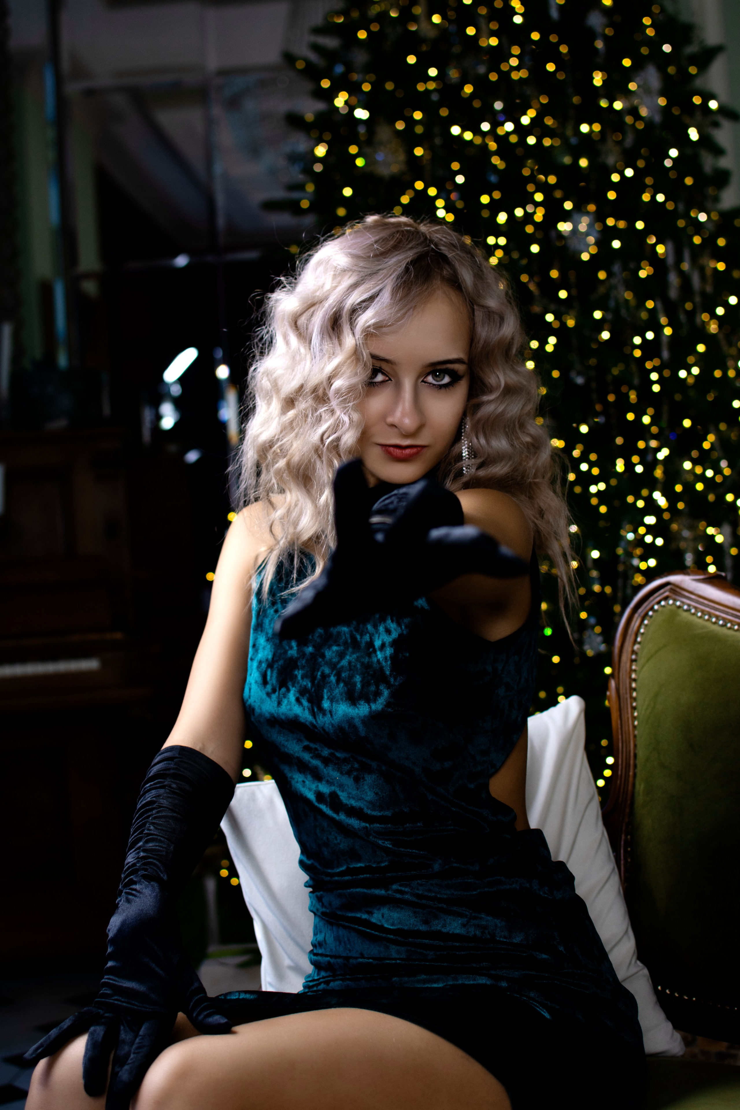 Девушка сидит на стуле и манит своей рукой