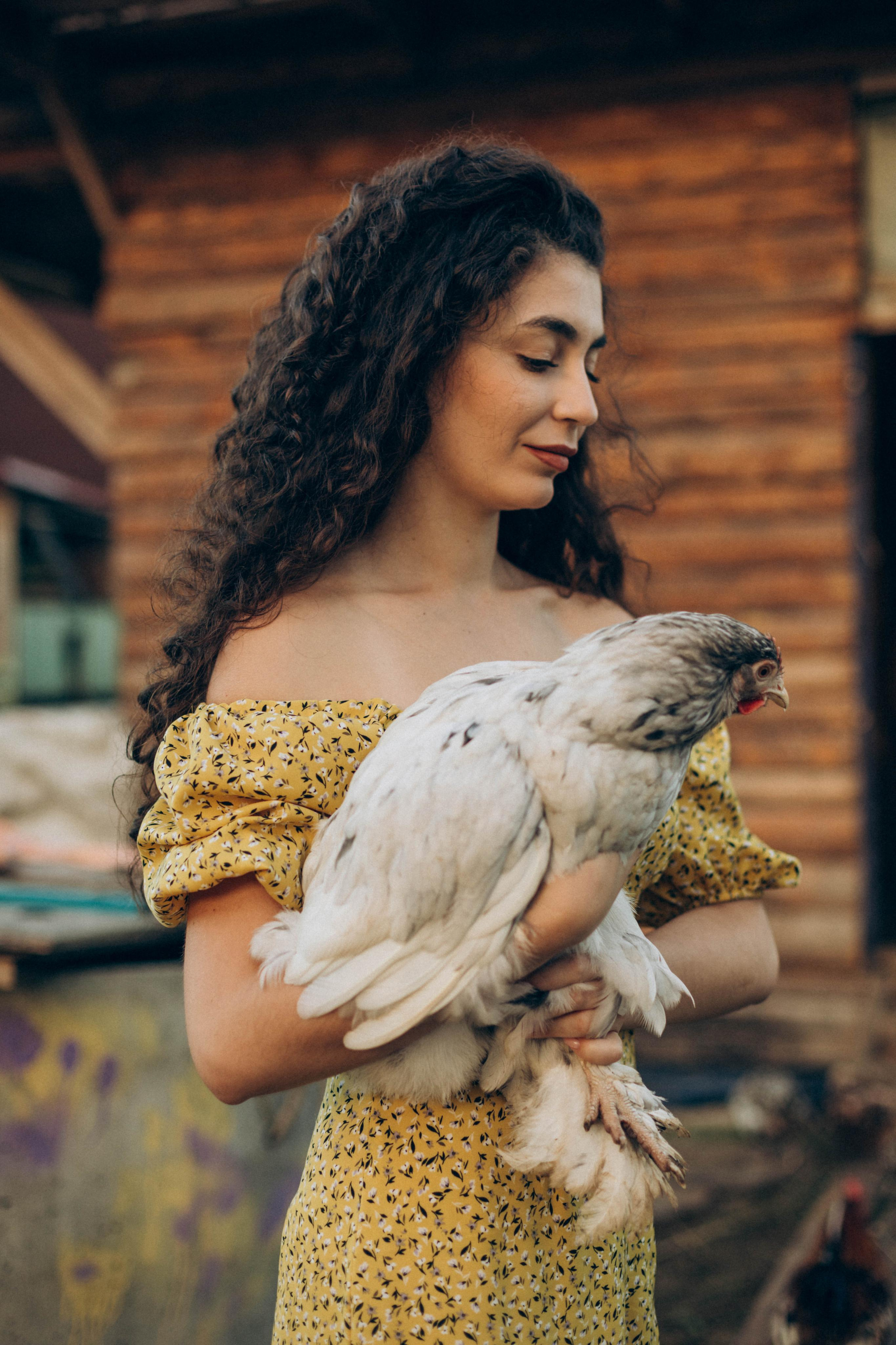 Девушка в деревенском стиле держит курицу на руках