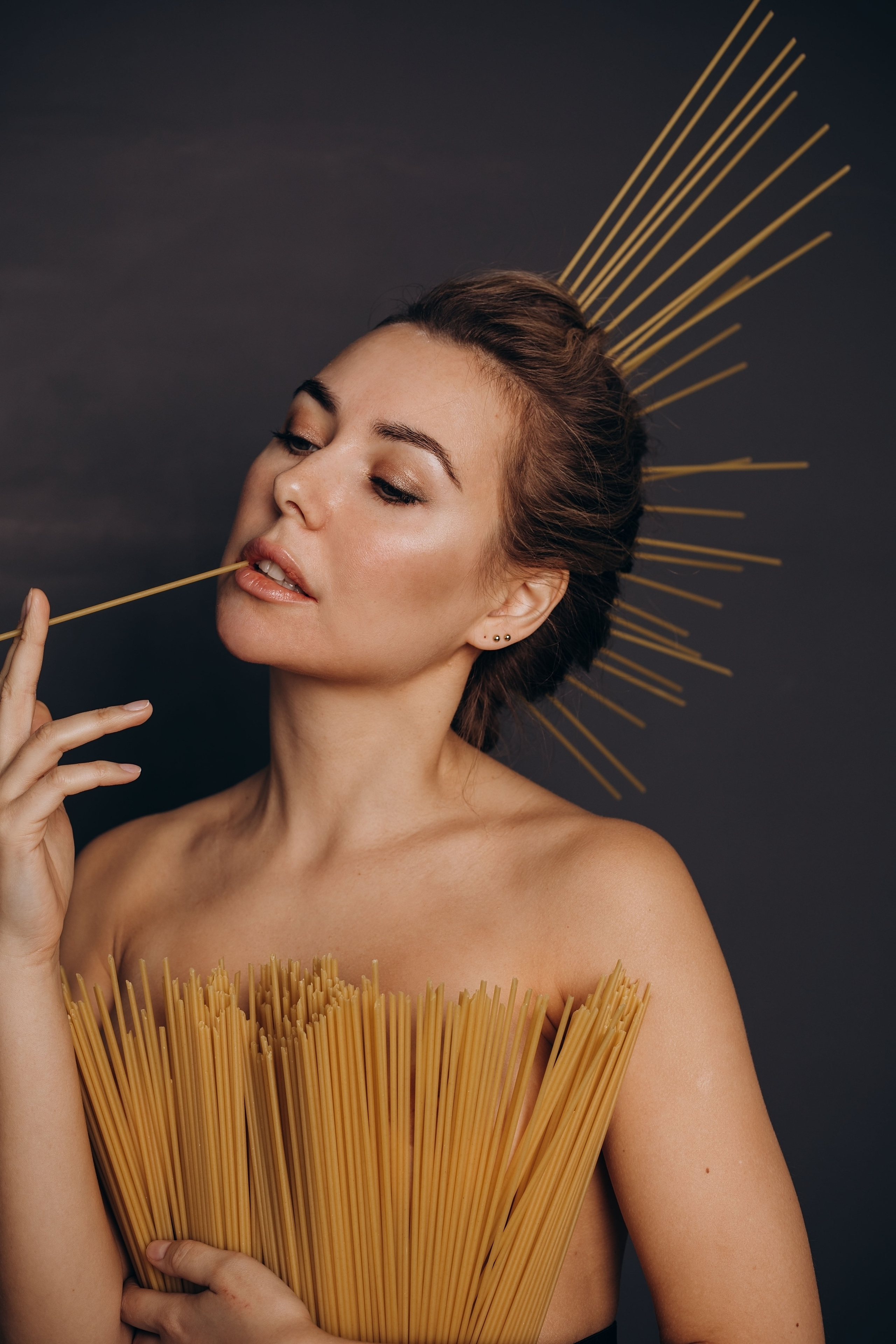 девушка на темном фоне прикуривает макароны как сигарету