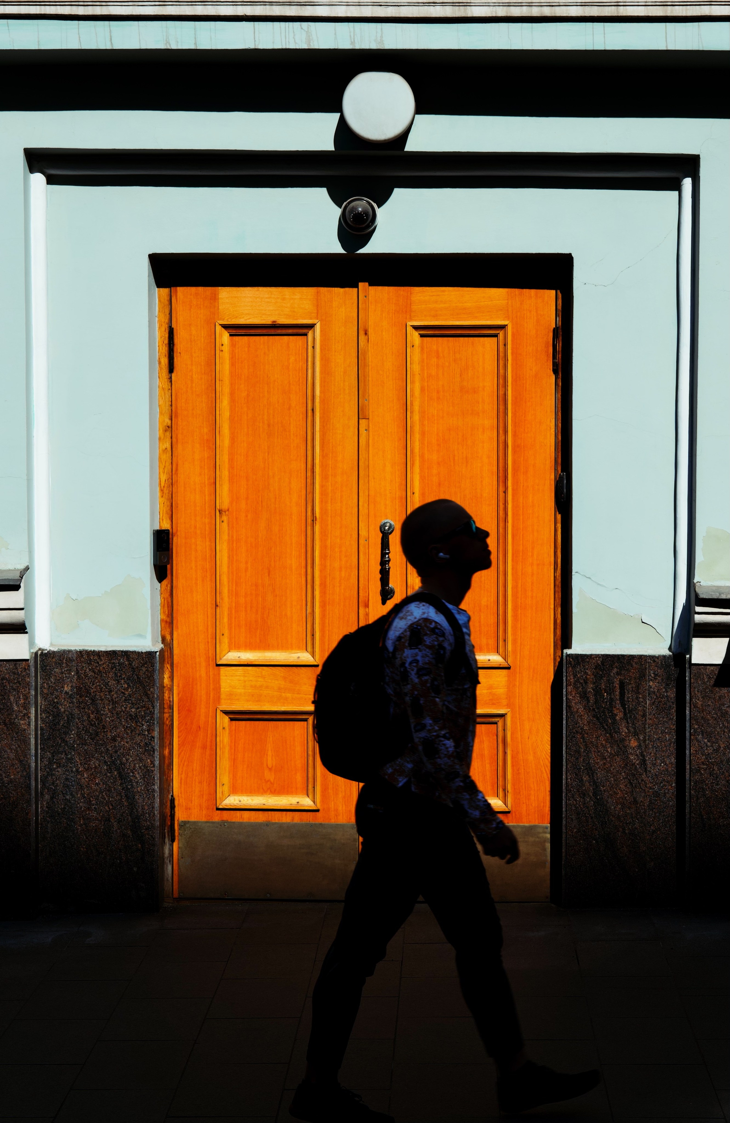 Силуэт мужчины на фоне оранжевой двери в переулках Арбата