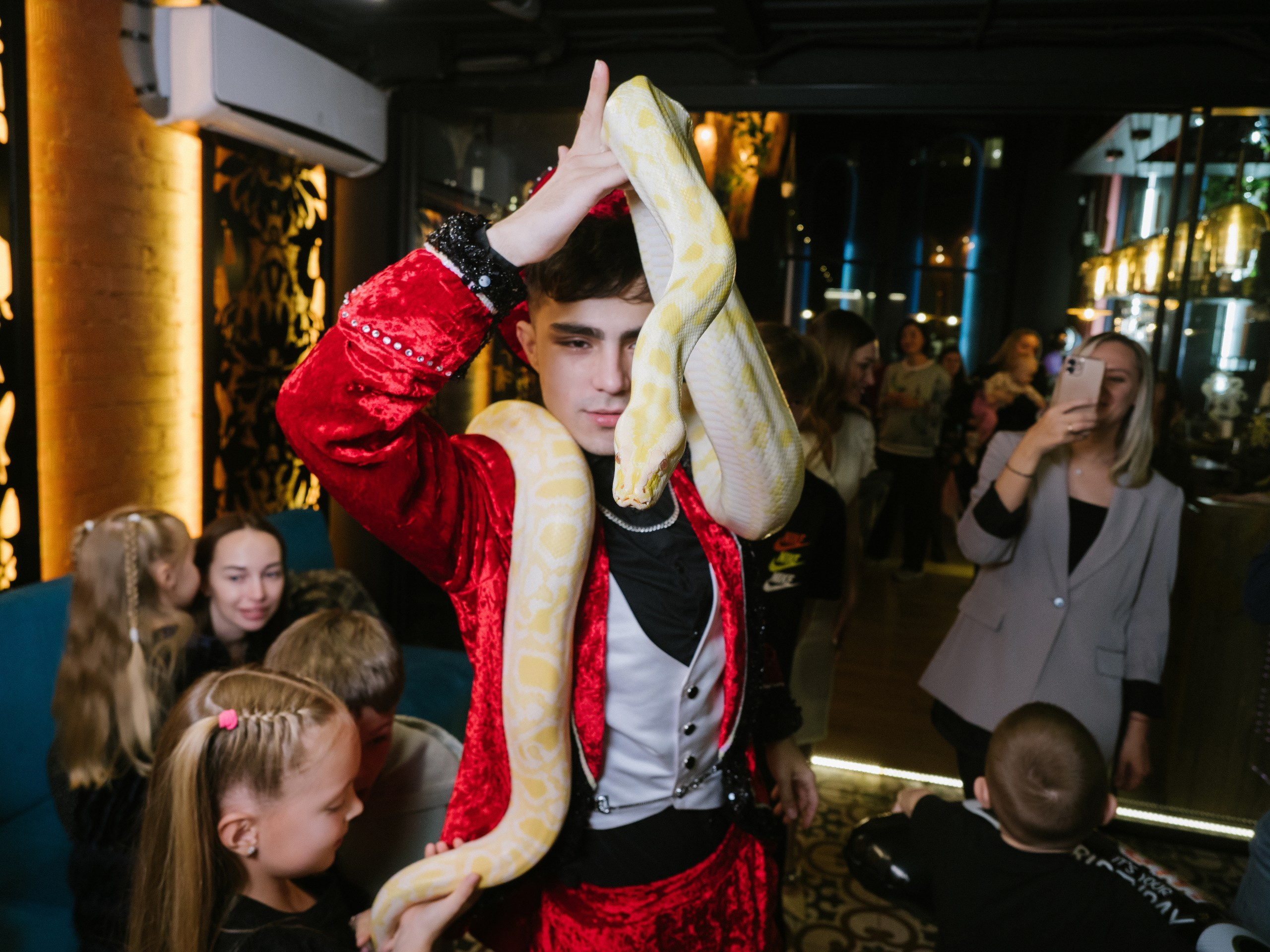 Фокусник держит в руке змею на детском дне рождения в Москве