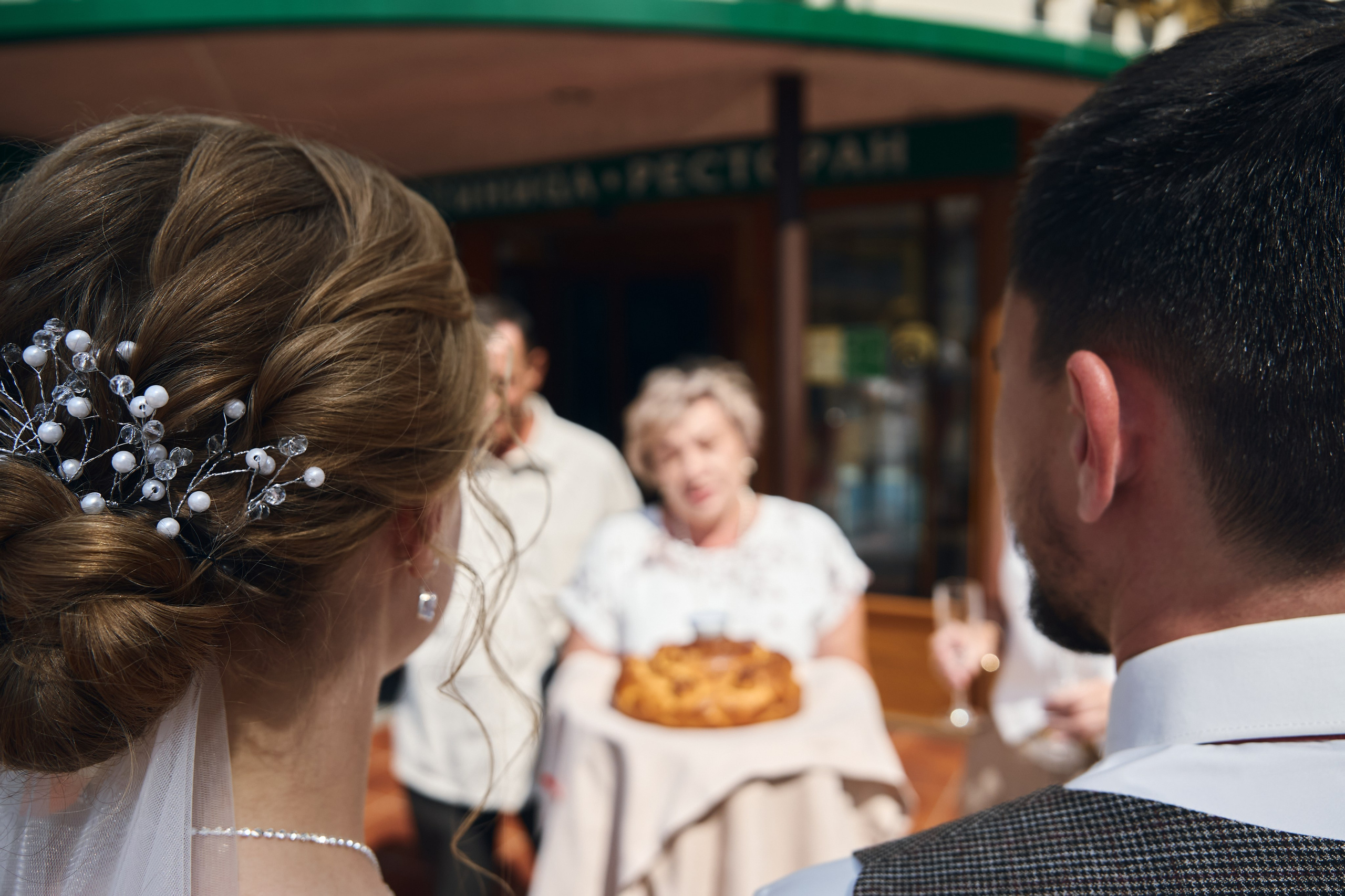 мама жениха выносит кулич молодоженам