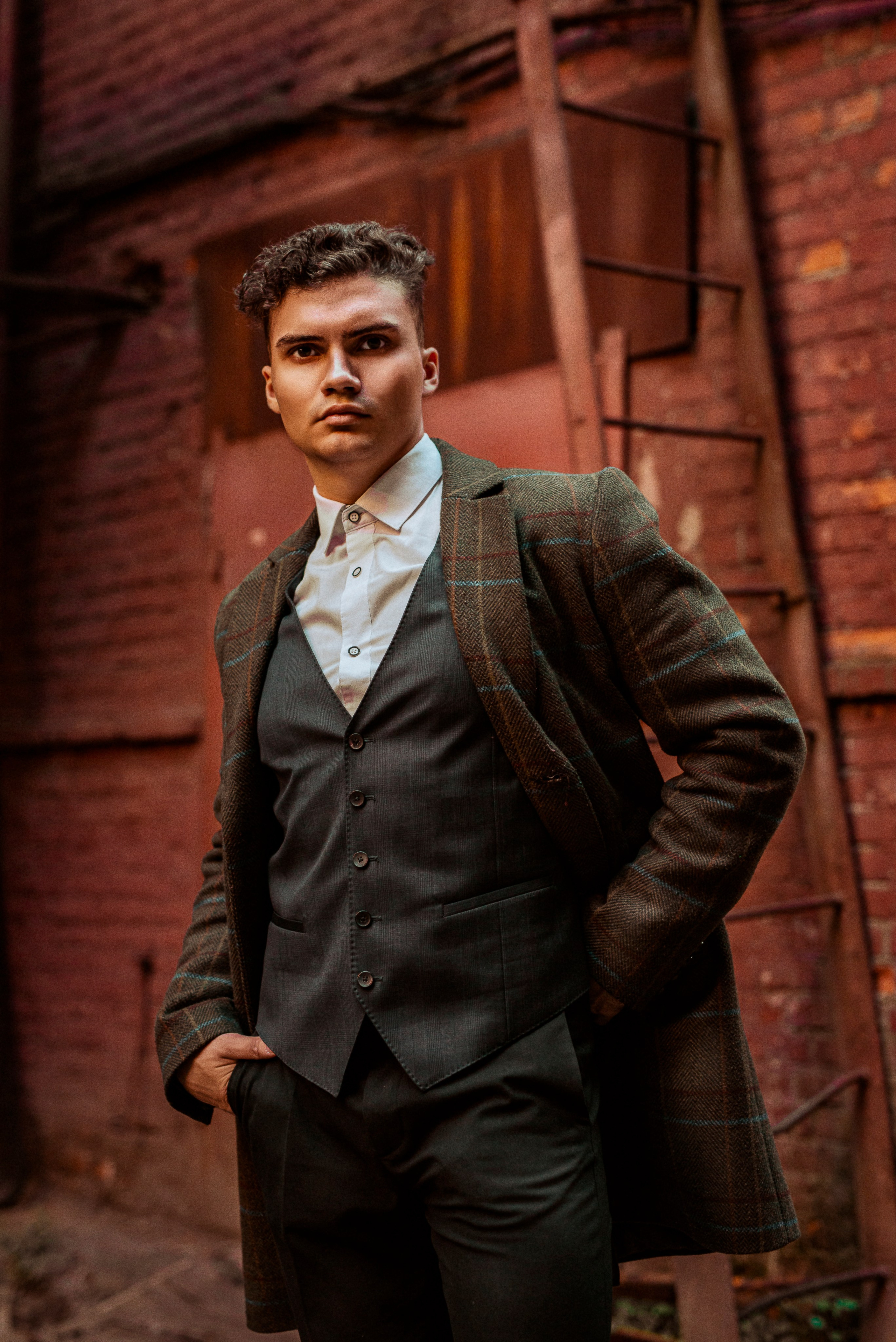Молодой человек изображен на фото на фоне стены из красного кирпича