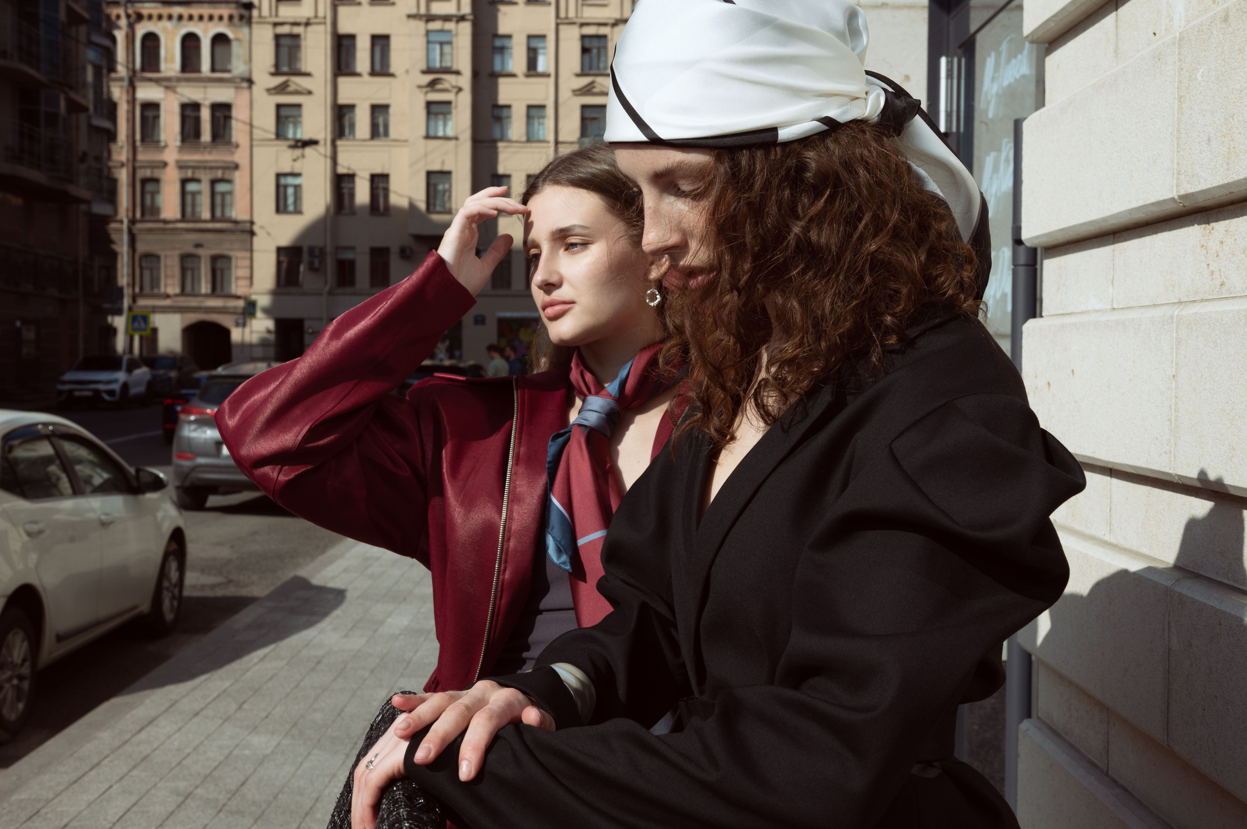 Две красивые девушки в дизайнерской одежде и шелковых дизайнерских платках стоят на фоне зданий