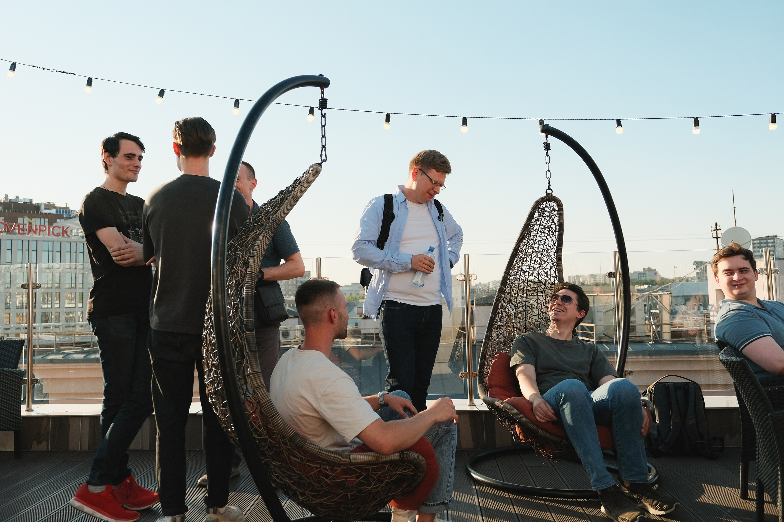 Корпоративное общение на вечеринке. Люди сидят в подвесных креслах икачаются.