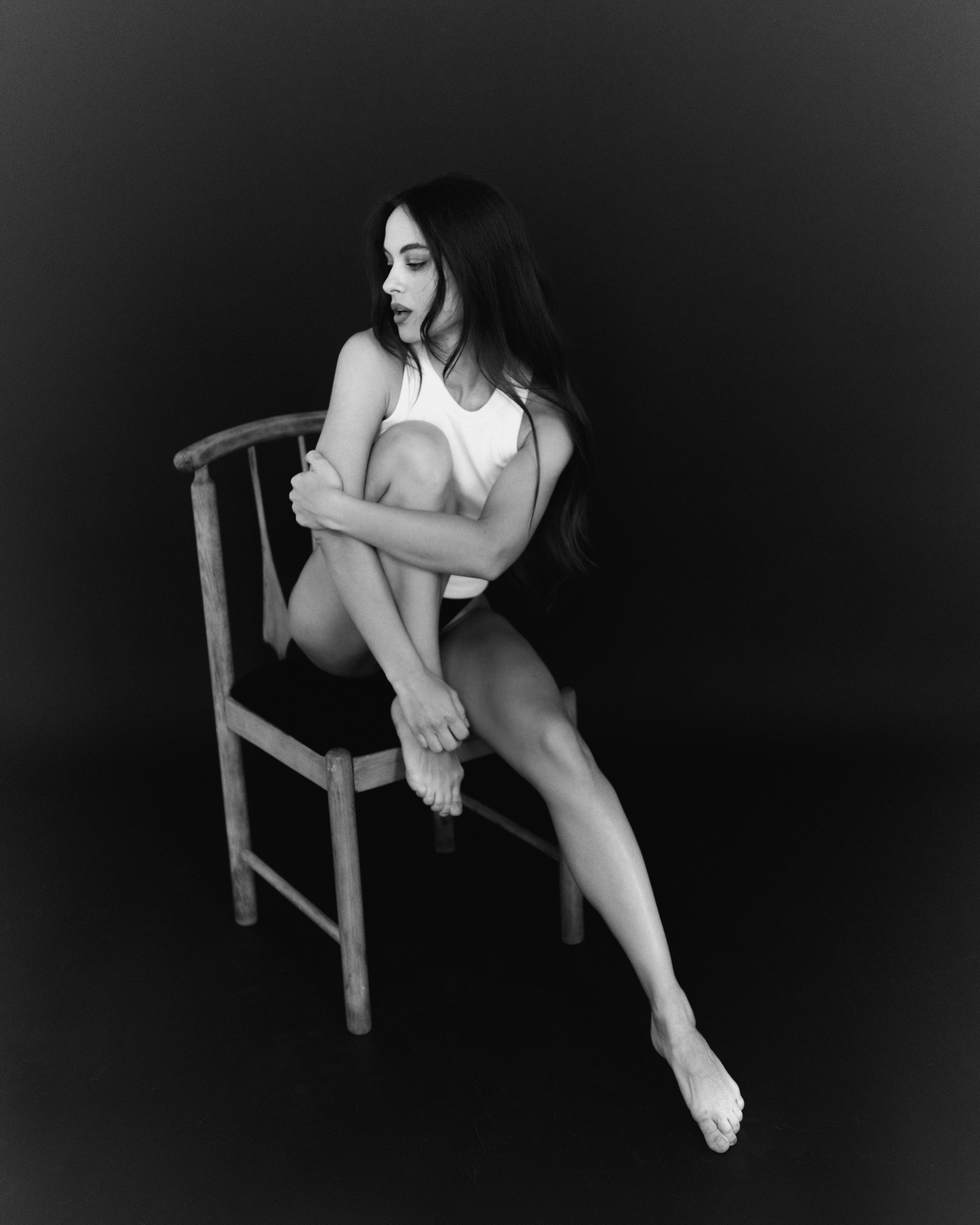Девушка сидит на стуле поджав ногу