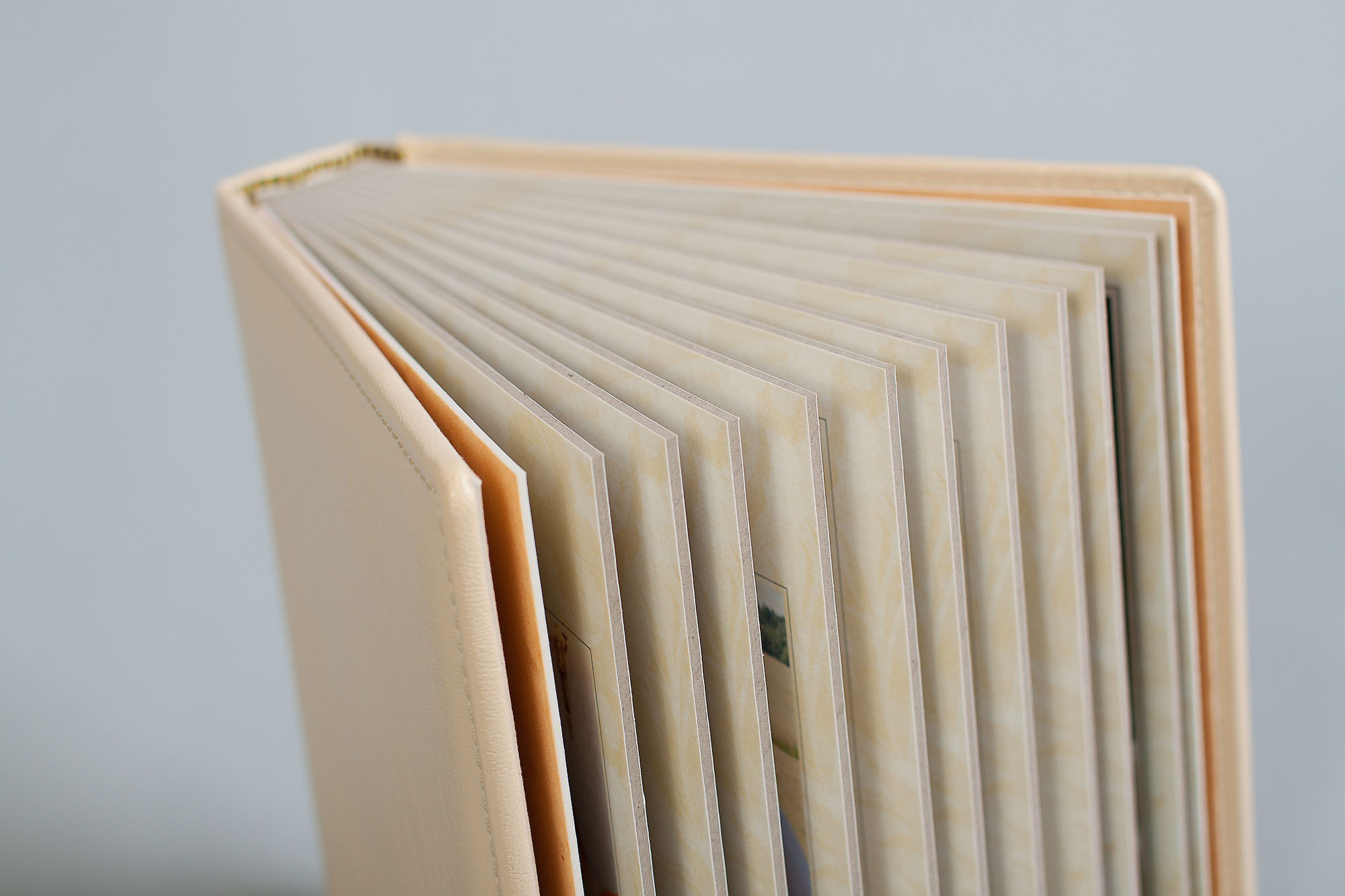 Бежевая свадебная фотокнига с жесткими листами  стоит вертикально.