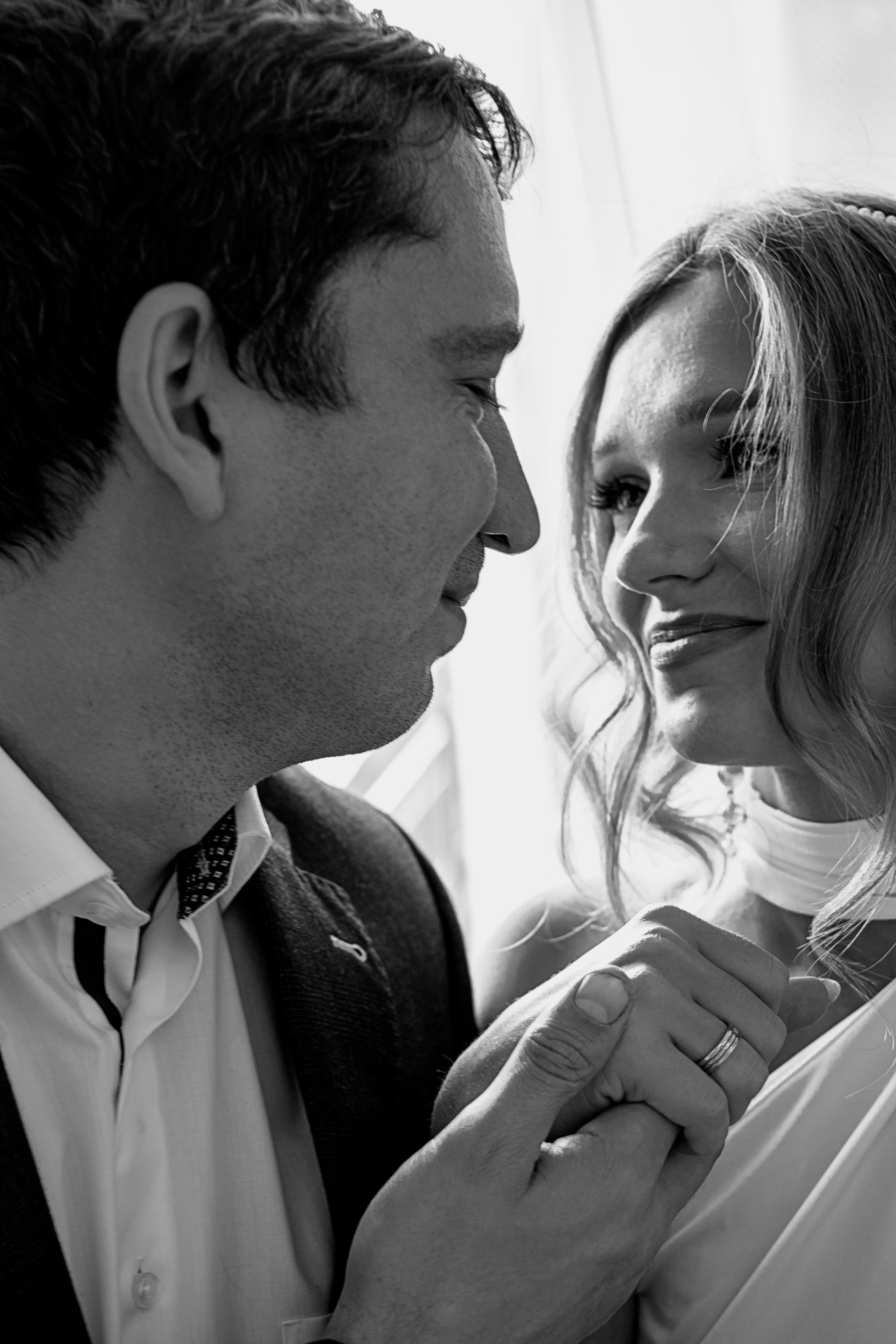 Жених смотрит на невесту, улыбается и держит ее руку