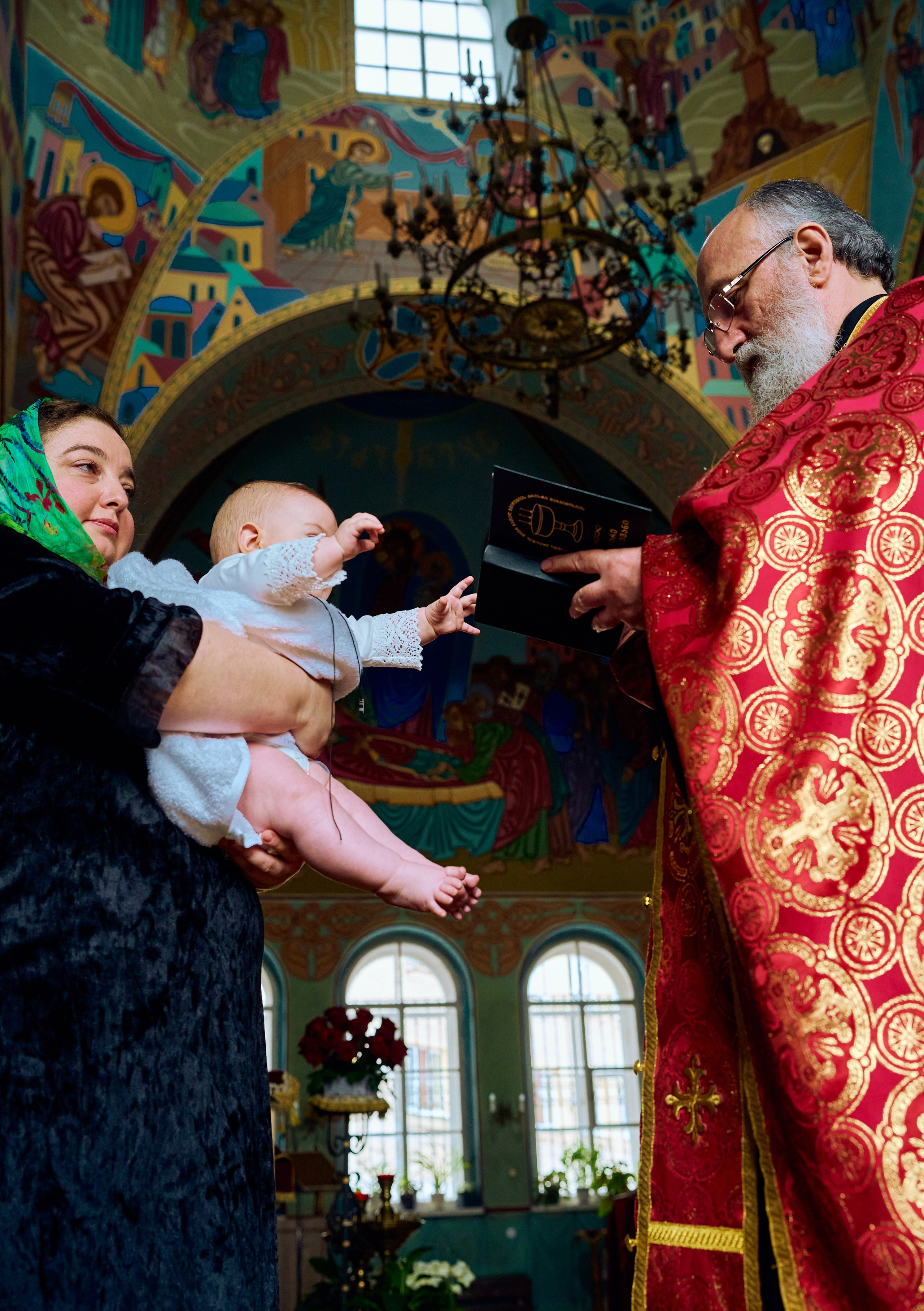 Женщина в платке держит ребёнка на руках, семейная фотосессия после крещения в церкви