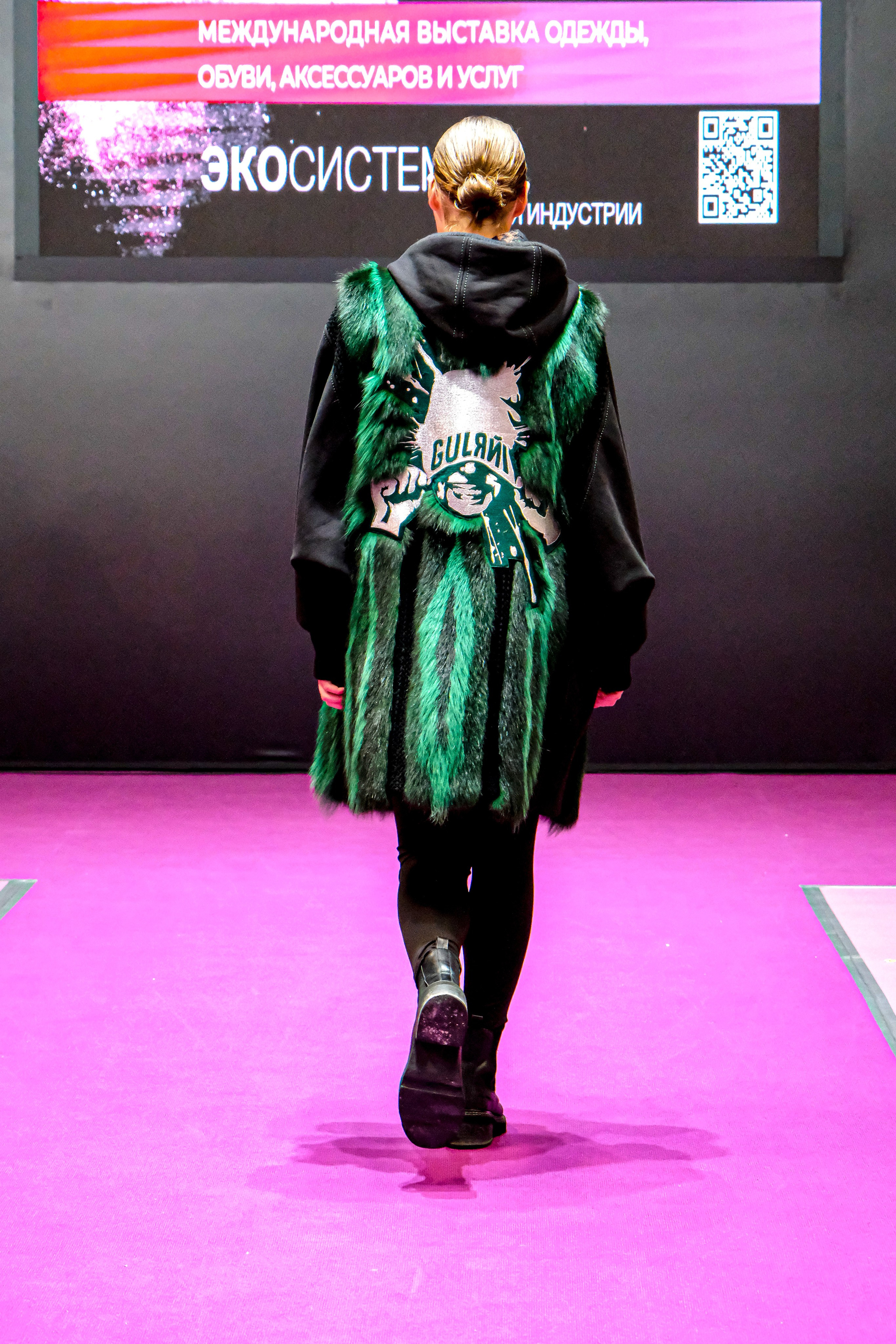  "Модели в ярких нарядах проходят по подиуму во время показа мод, освещенные яркими софитами и окруженные восторженными зрителями."